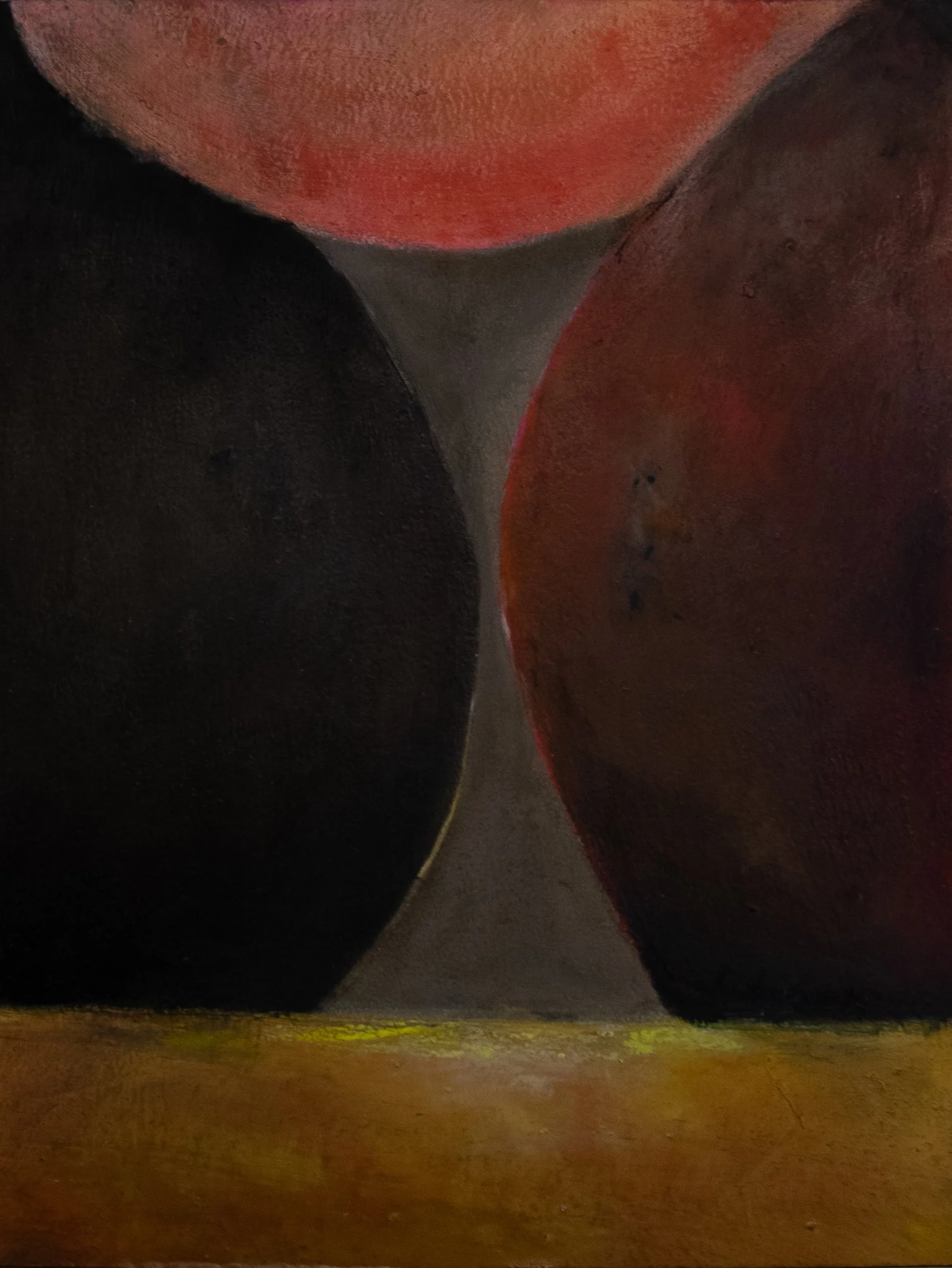 Close-up of three black, red, and brown oil painting arranged on a yellow surface.