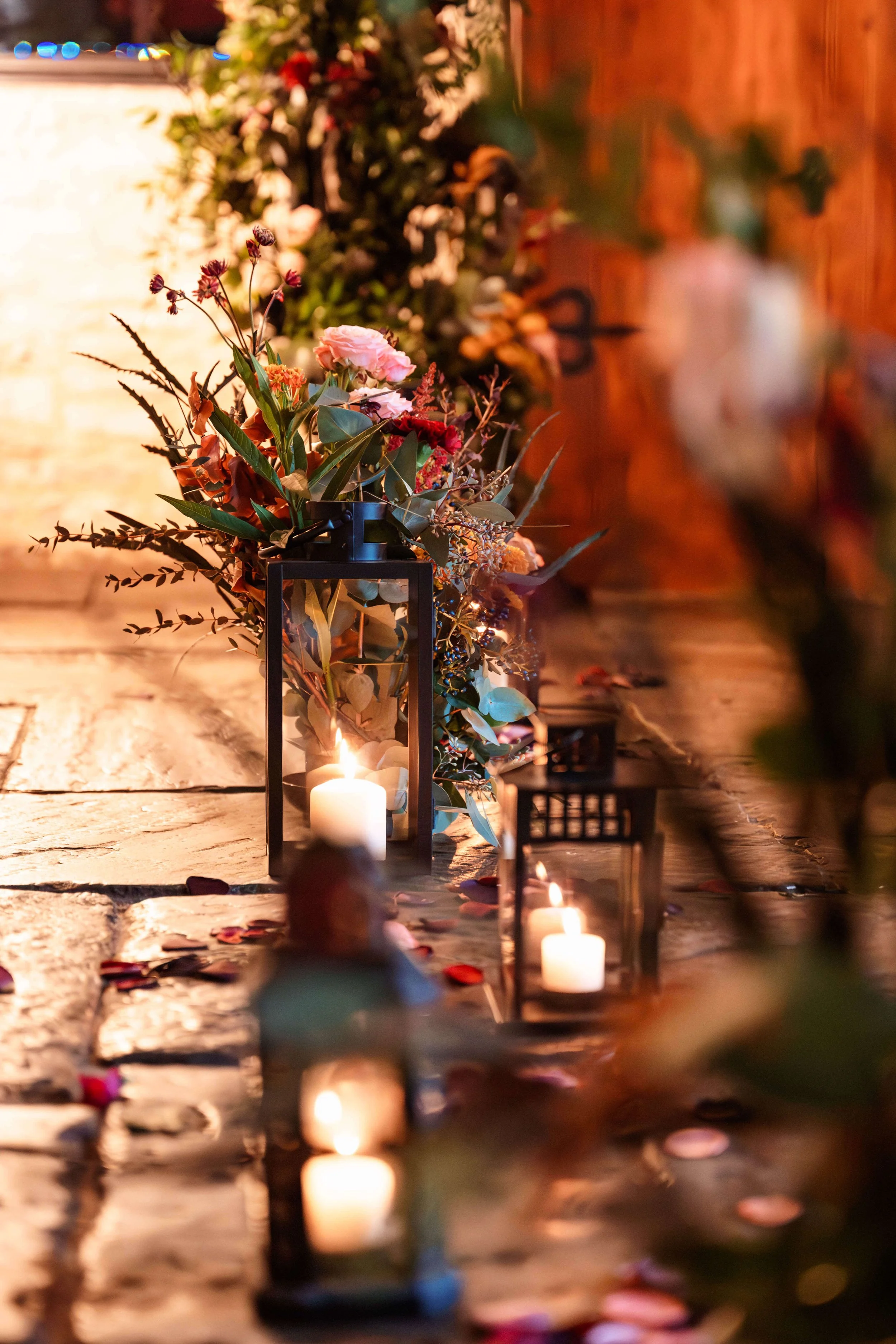 Decorative arrangement of candles and flowers on a stone surface, creating a warm and romantic ambiance.