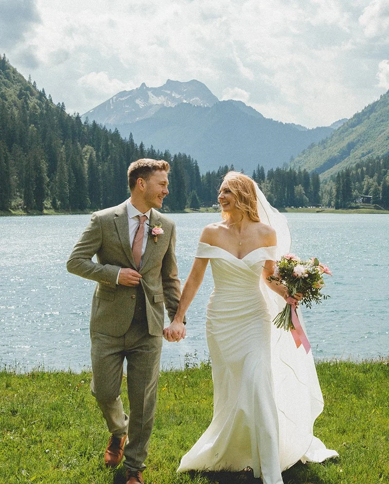 Happy wedding couple smiling in front of Lake Montriond with the Morzine mountains in the background border