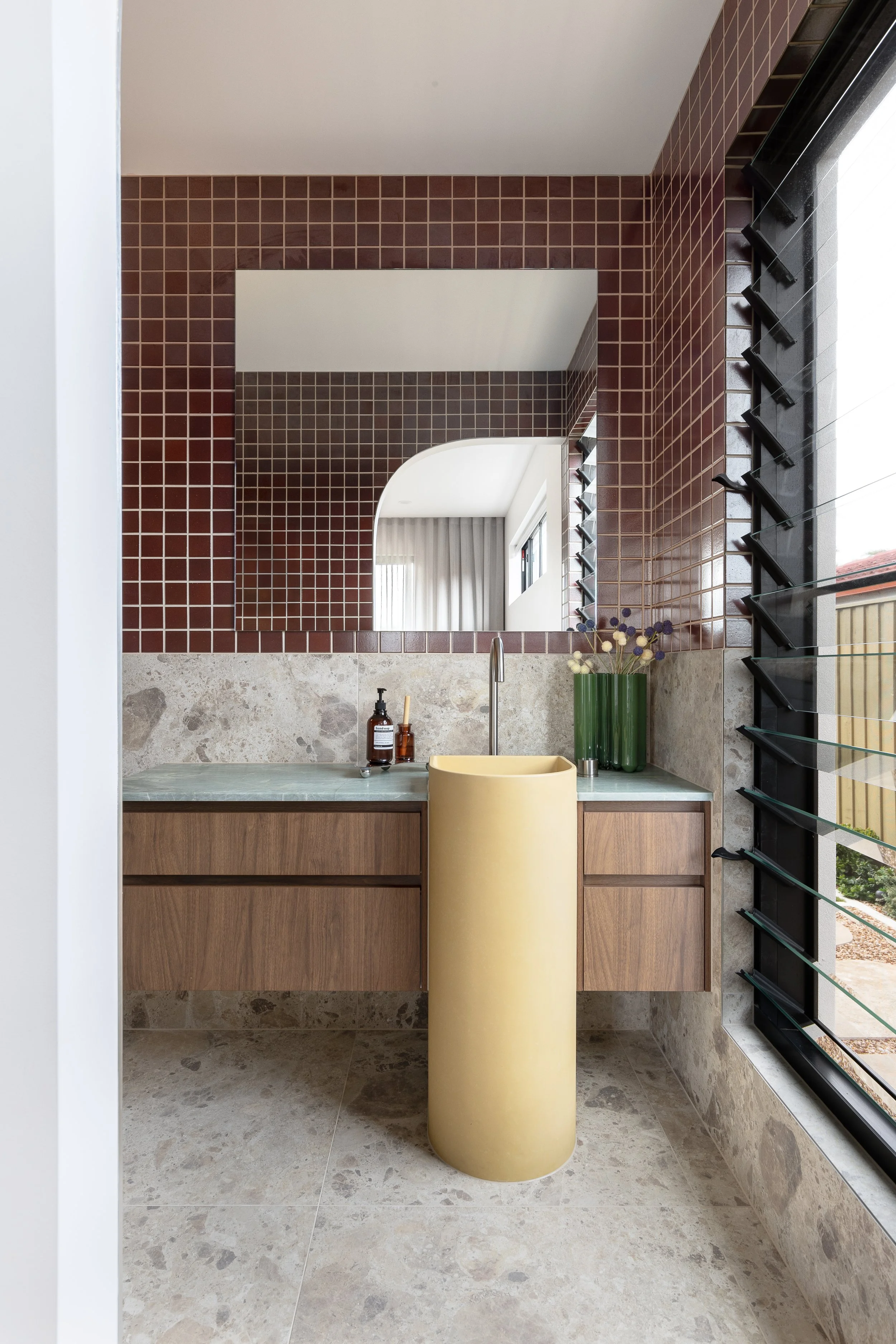 colour pop interior bathroom yellow concrete pedestal basin and moody red square mosaics
