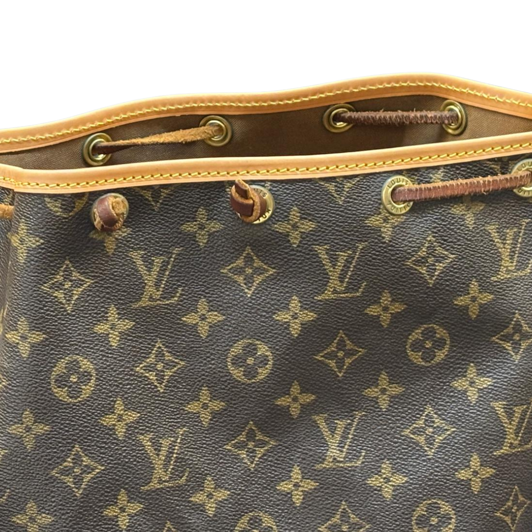 Nahaufnahme eines Louis Vuitton Monogramm-Taschenrests mit goldfarbenen Ösen und braunen Lederzügen.