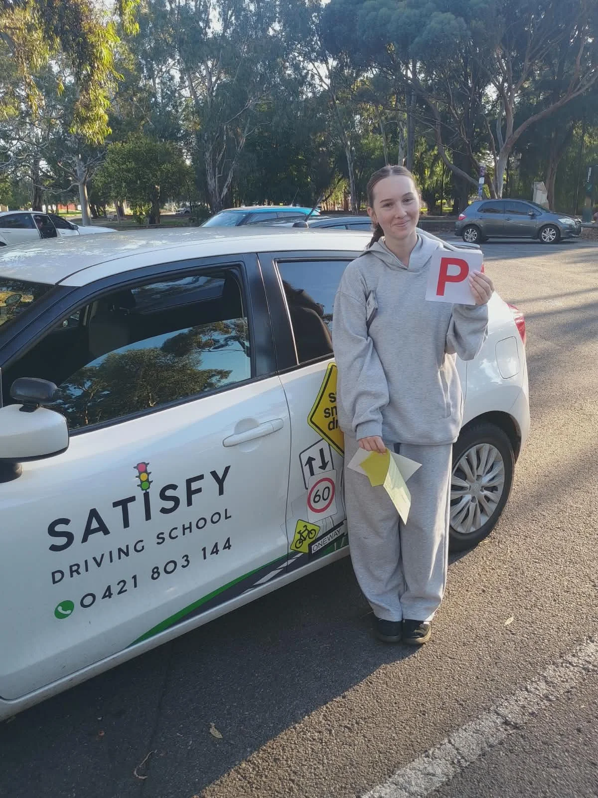 Student holding P plates after cracking their driving test Satisfy Driving School