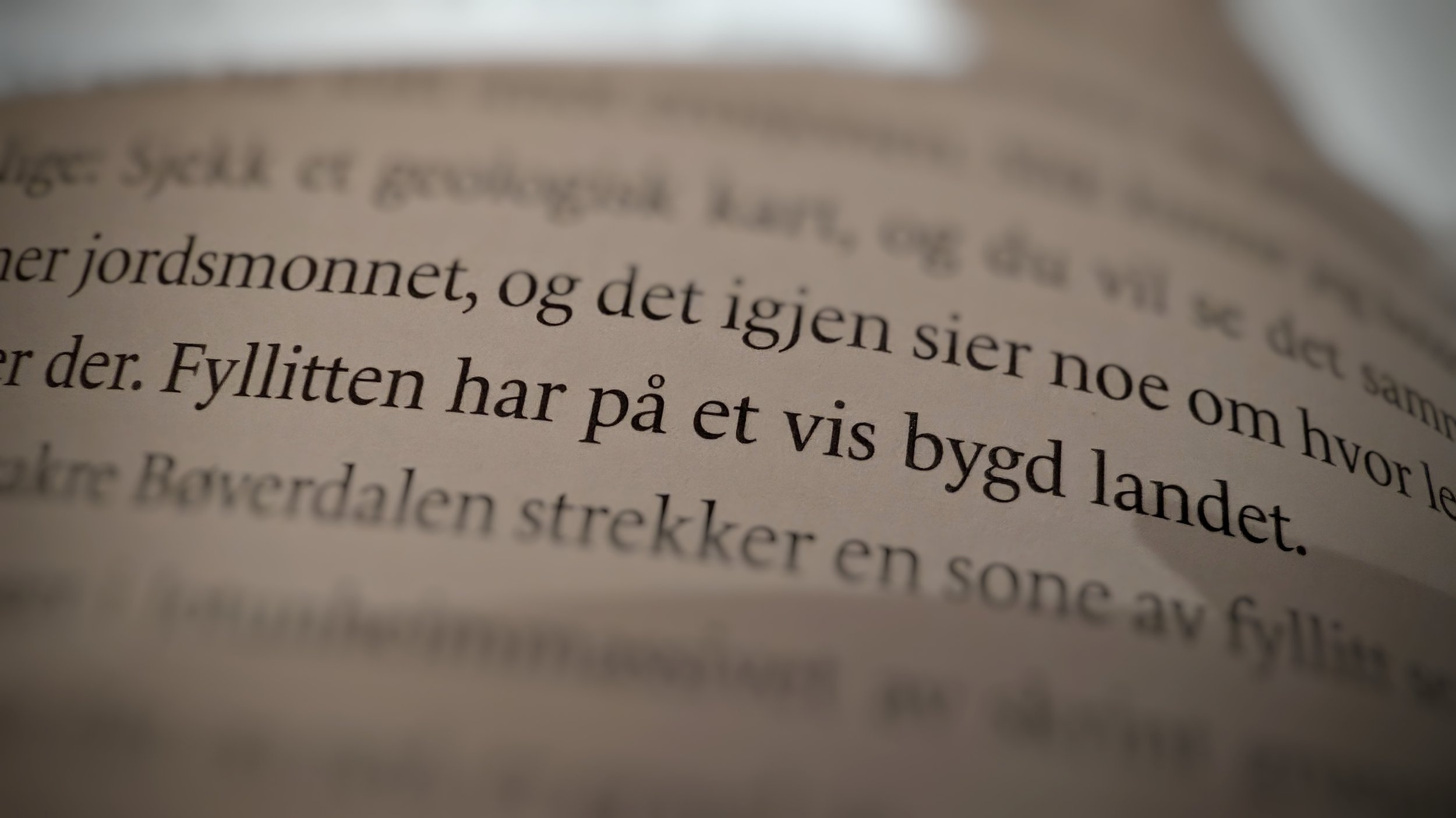 Close-up of text in Norwegian on a page, with focus on the sentence "Fyllitten har på et vis bygd landet."