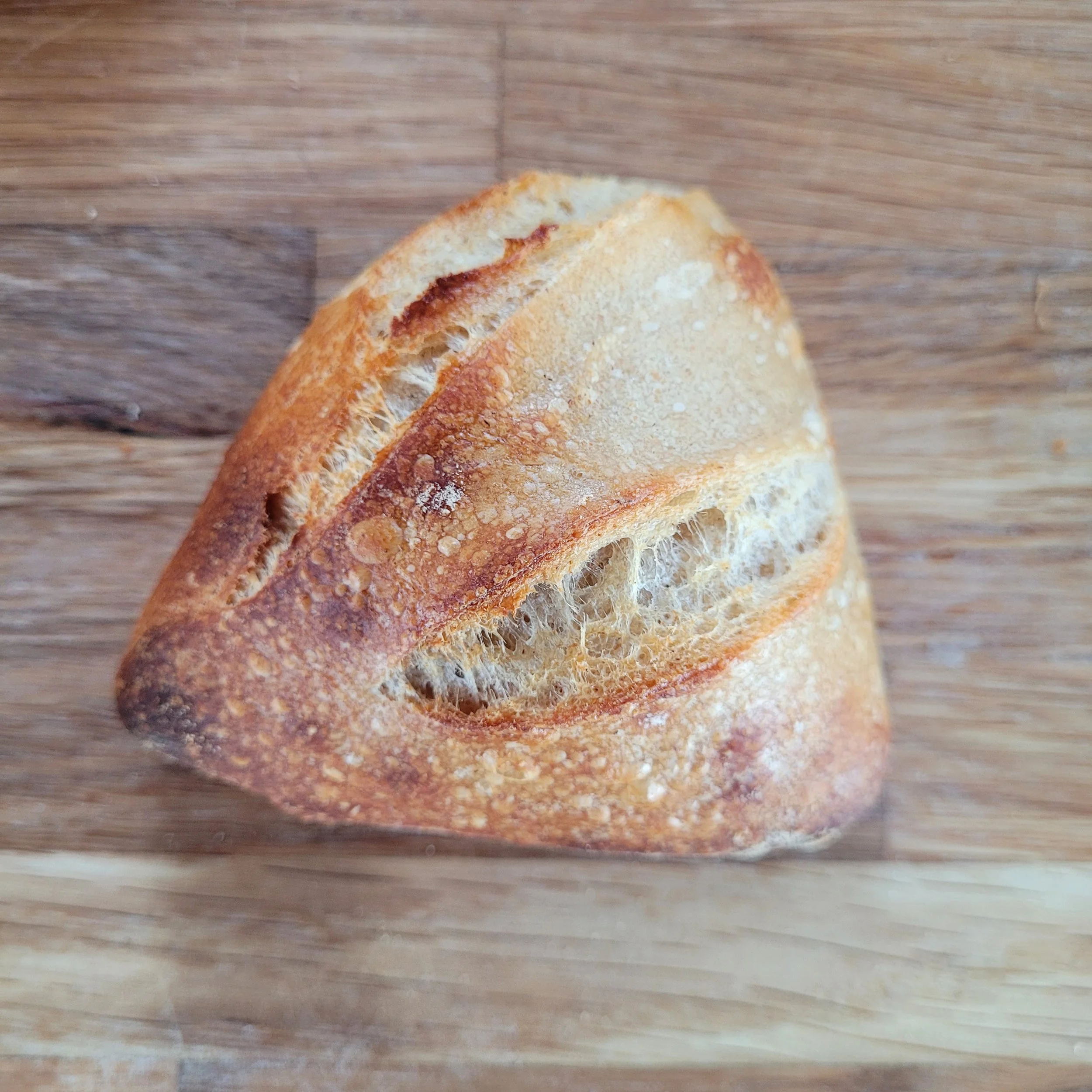 A piece of rustic artisan bread on a wooden surface.