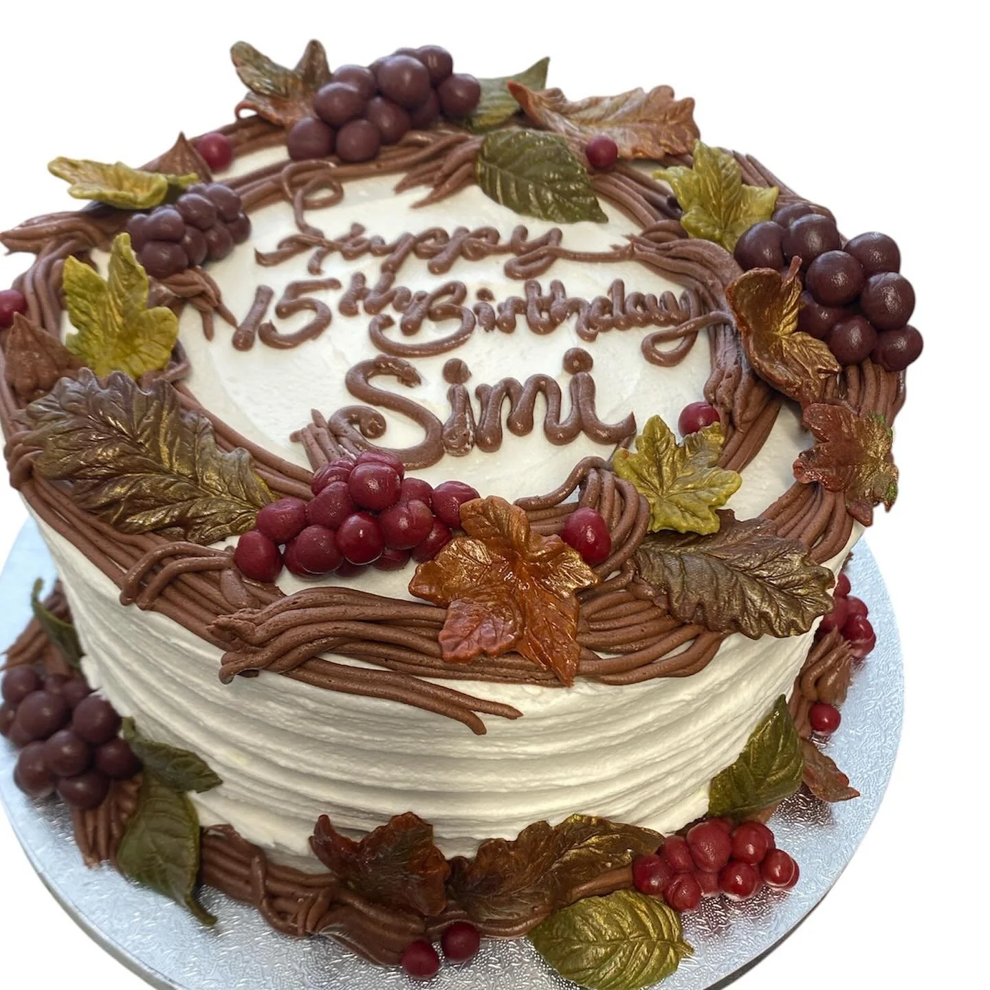 Frosted chocolate cake with chocolate frosting twigs sugar berries and sugar leaves.