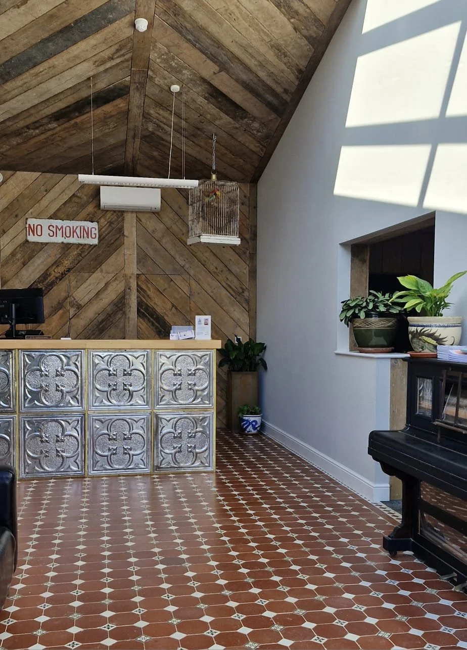 Interior of a reception area with a wooden accent wall, decorative tile front desk, and potted plants. Includes a