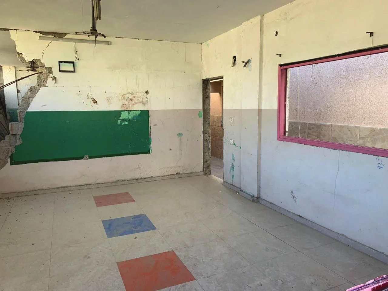 Classroom interior — The chalkboard survived. The desks were looted. This room will be a classroom again.