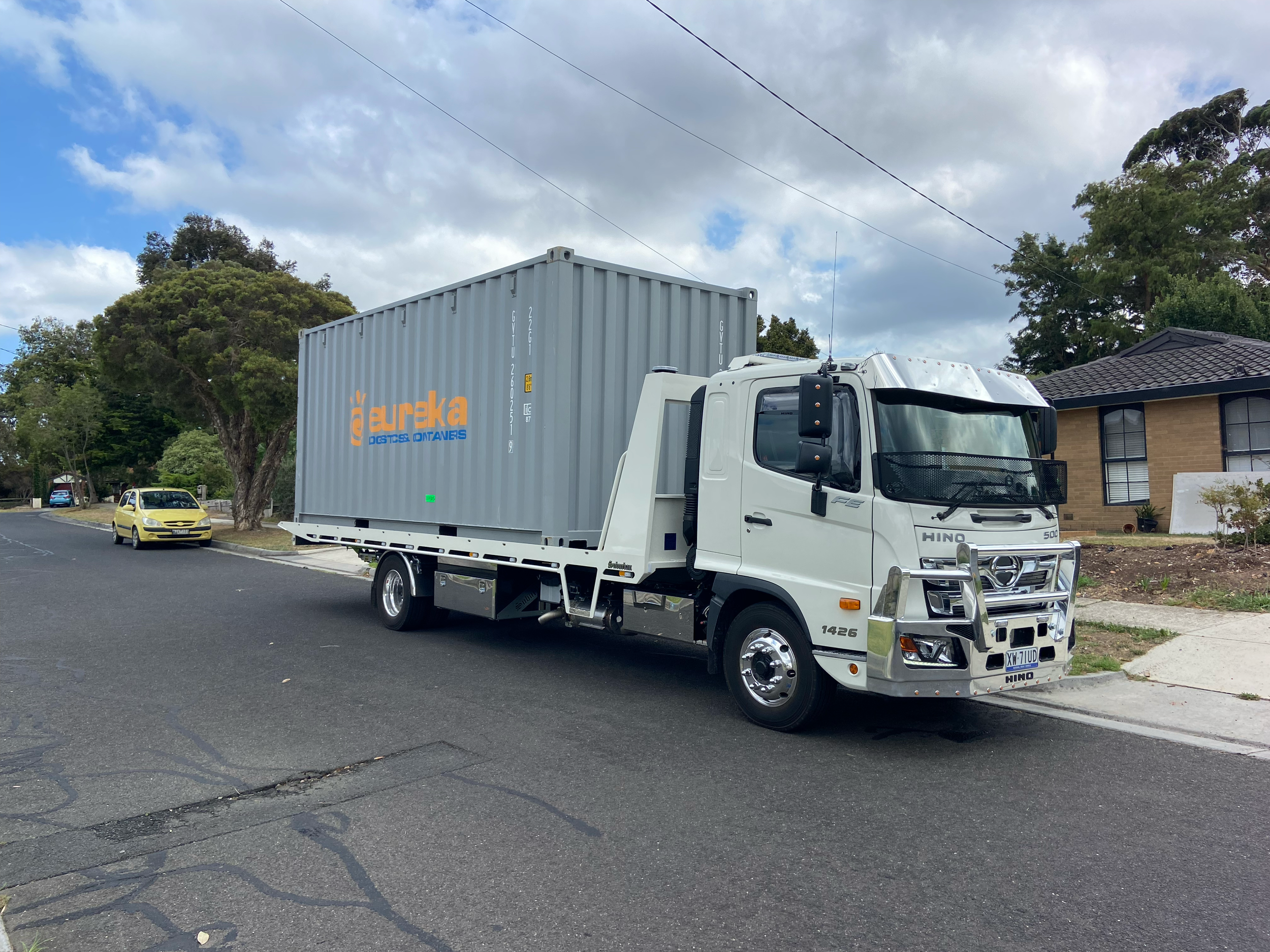 White commercial truck with container parked on a suburban street.