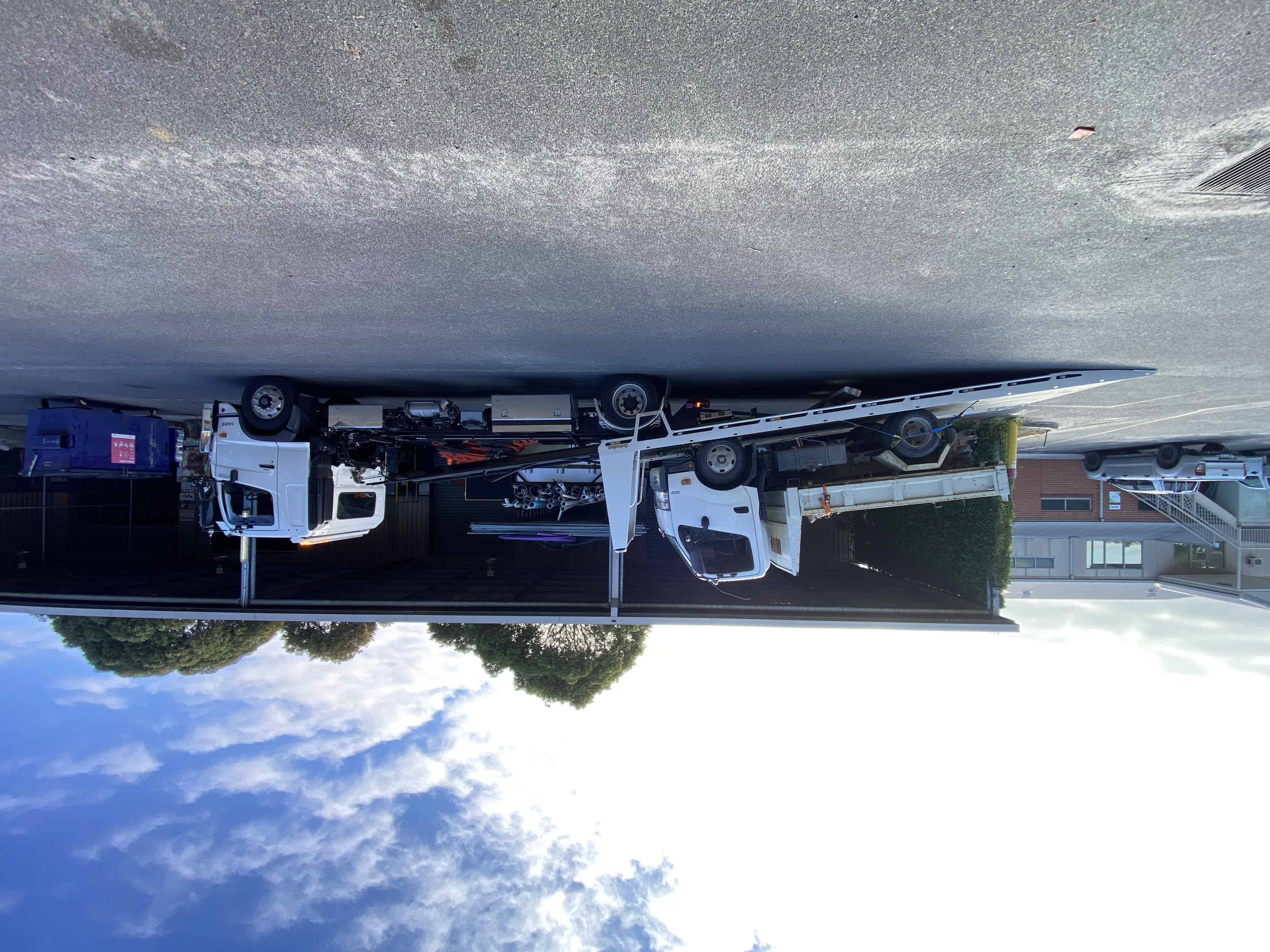 Two trucks with flatbeds parked outside a building.