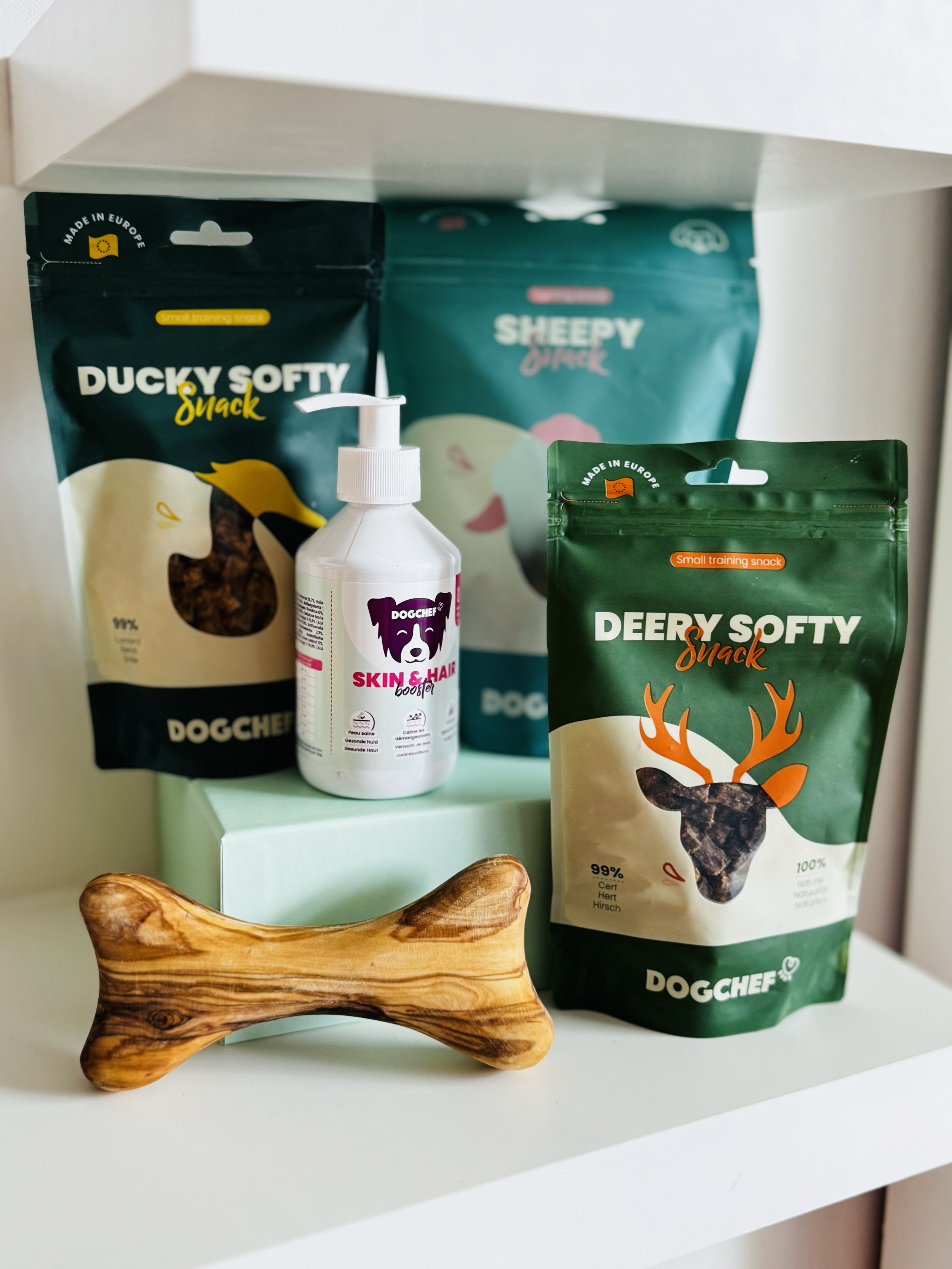 Divers sacs de friandises pour chien (renne, canard, boeuf, poulet, mouton), des os en bois d'olivier et un produit pour les poils et la peau de la marque française Dog Chef.