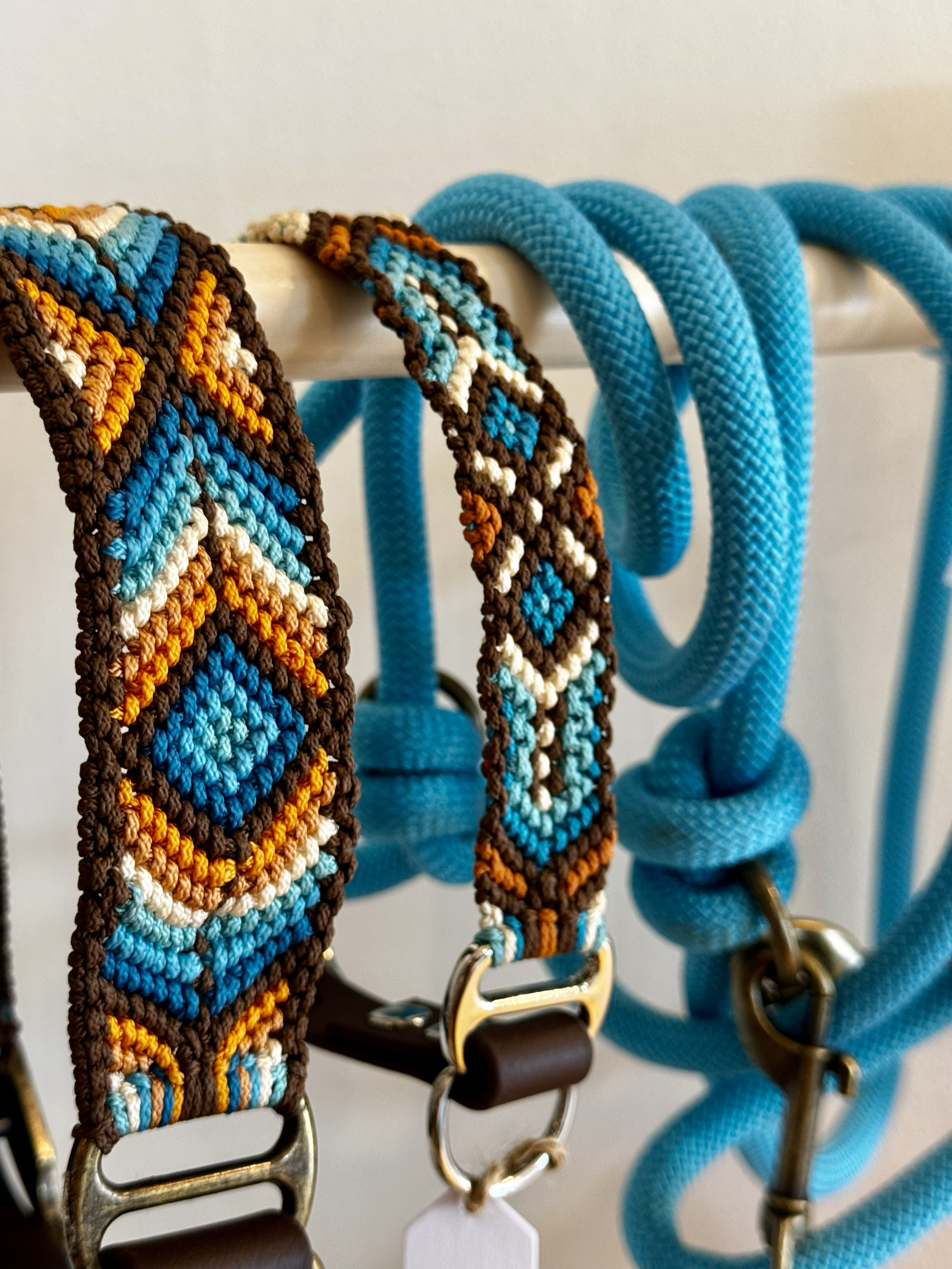 Laisses et colliers pour chiens, une en macramé colorée avec des motifs géométriques en bleu, orange, marron, blanc de la marque belge "Comme Cha et chiens".