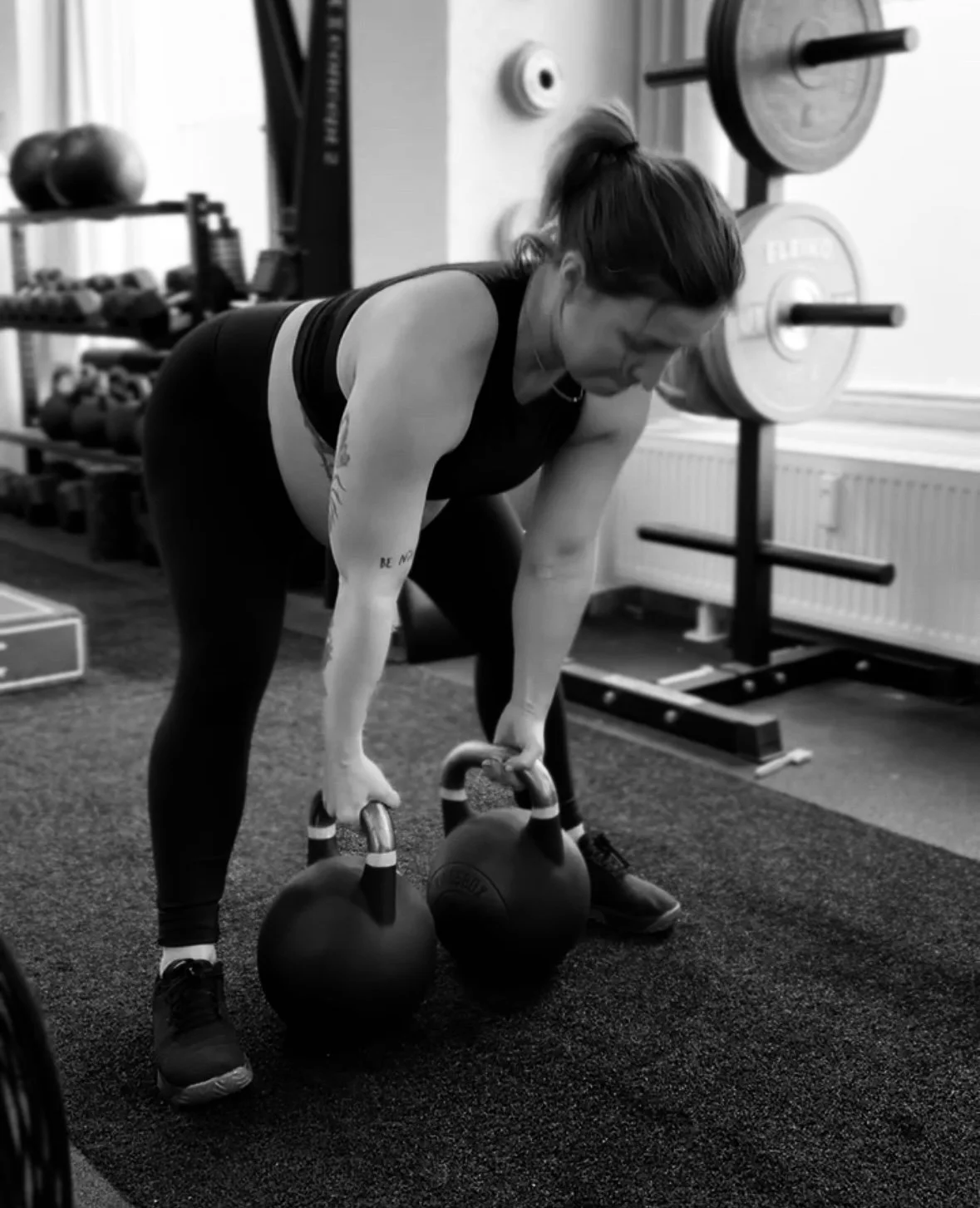 Frau beim Krafttraining mit Kettlebells im Fitnessstudio.