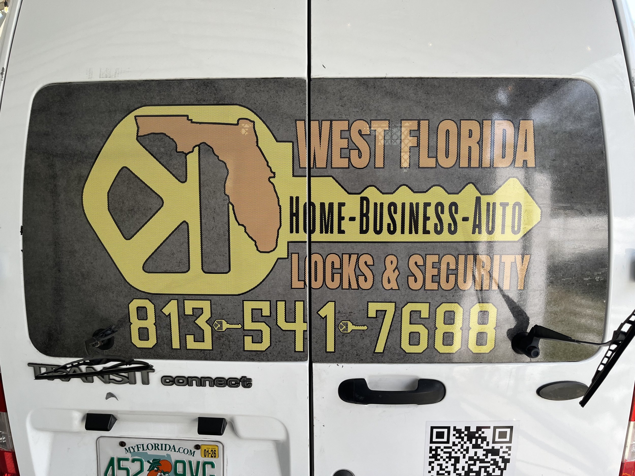 A decal on a vehicle displaying the logo and contact information for West Florida Home-Business-Auto Locks & Security, including a map outline of Florida, a phone number, and a QR code.