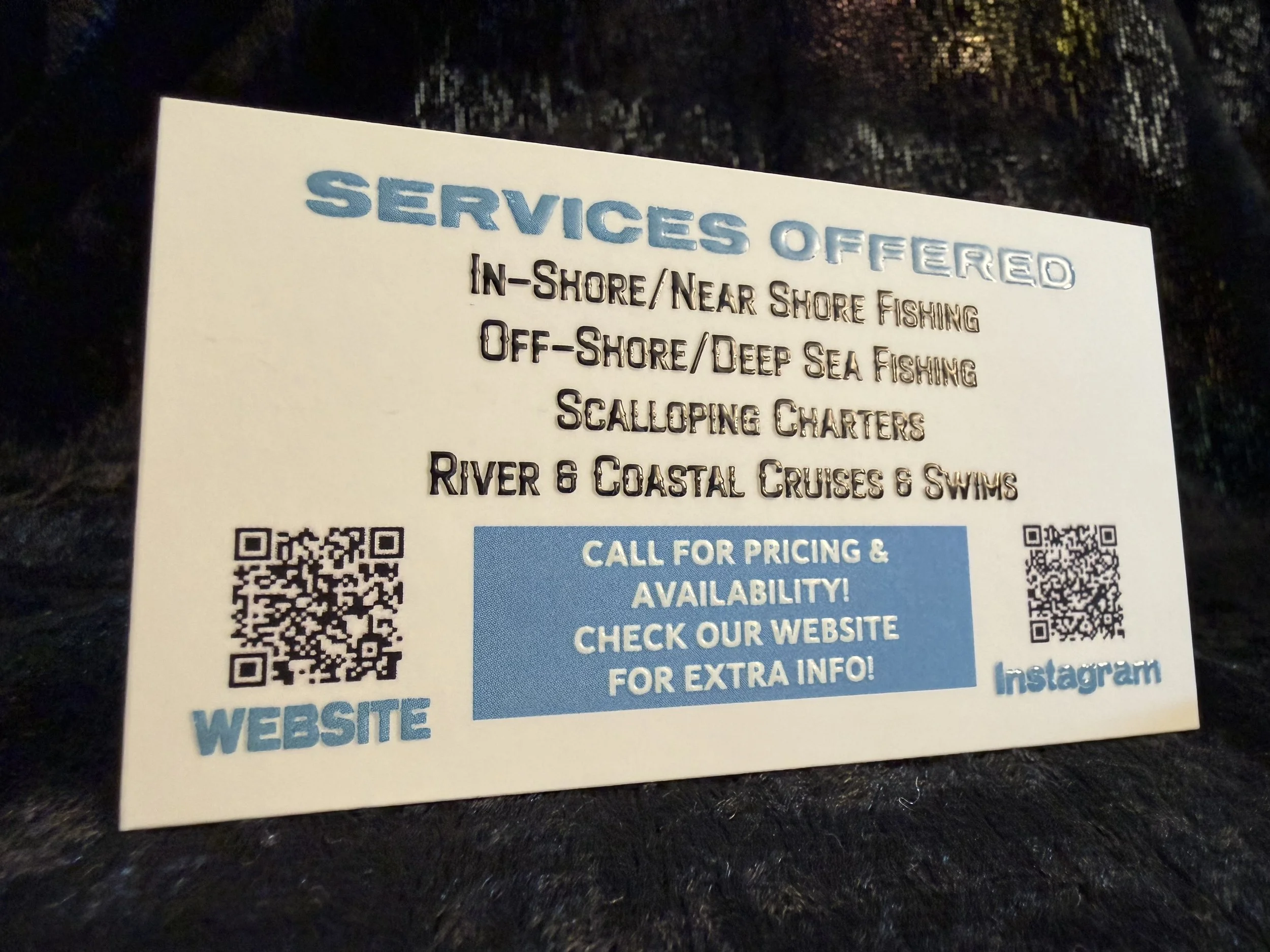 Business card listing fishing and cruise services, including in-shore and off-shore fishing, scalloping, and river and coastal cruises. Contains QR codes for website and Instagram, with a blue call-to-action box.