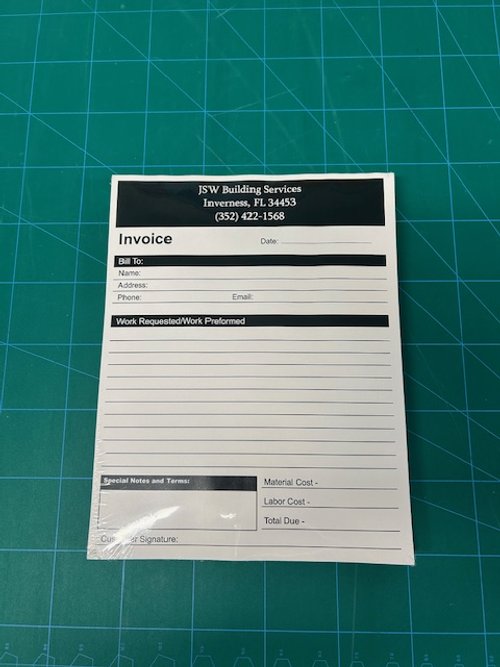 A printed invoice from ISW Building Services, located in Inverness, FL, placed on a green cutting mat with measurement grid lines.