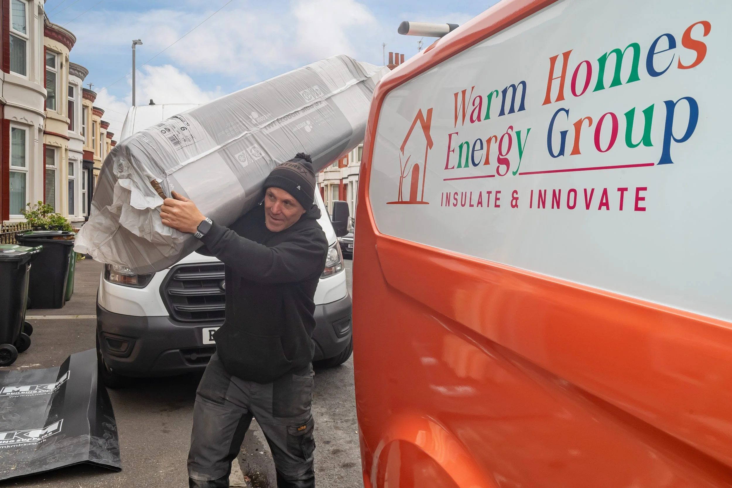 Insulation installer carrying loft insulation material for installation in North Wales residential property