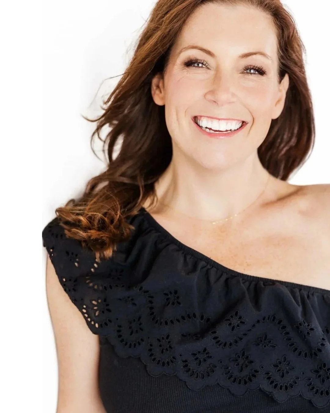 Here is an image of Gina Woelfel, owner of Mood Edit & Co, a digital clarity agency. Gina has long red hair, blue eyes and is wearing an off the shoulder black shirt and smiling