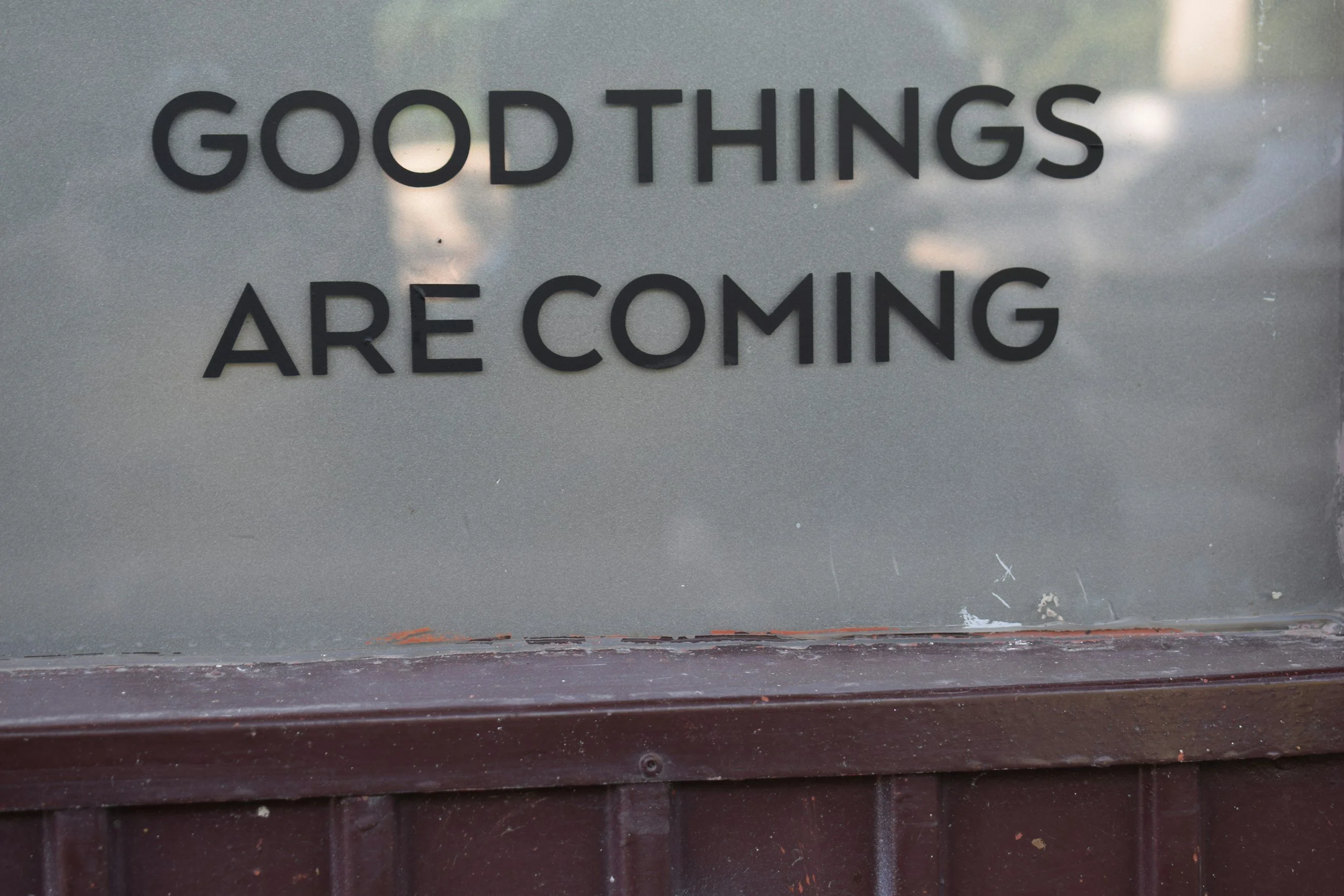 Sign with the words 'Good Things Are Coming' on a gray surface.