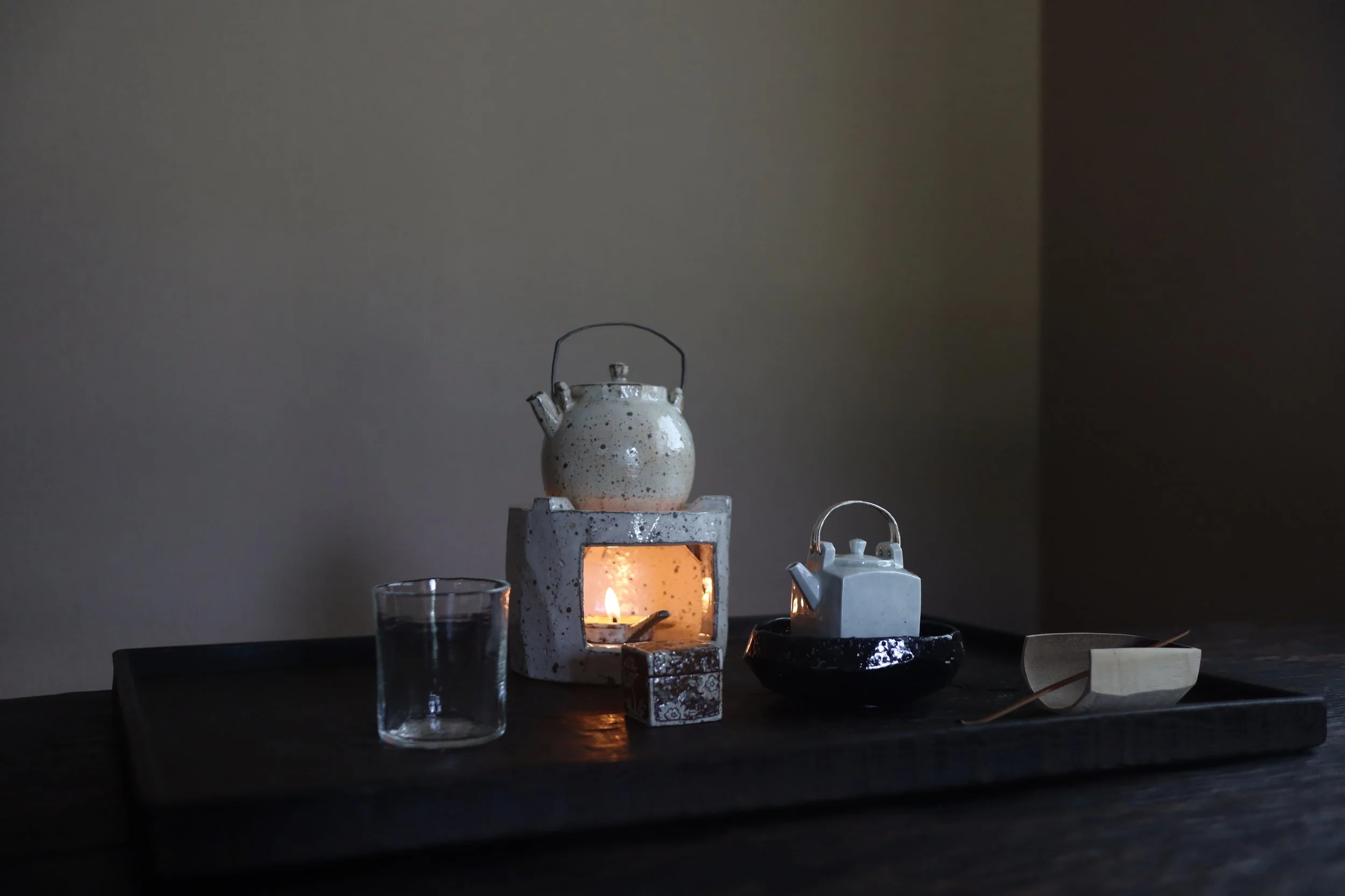 Pouring tea from a white teapot into a cup on a wooden table.