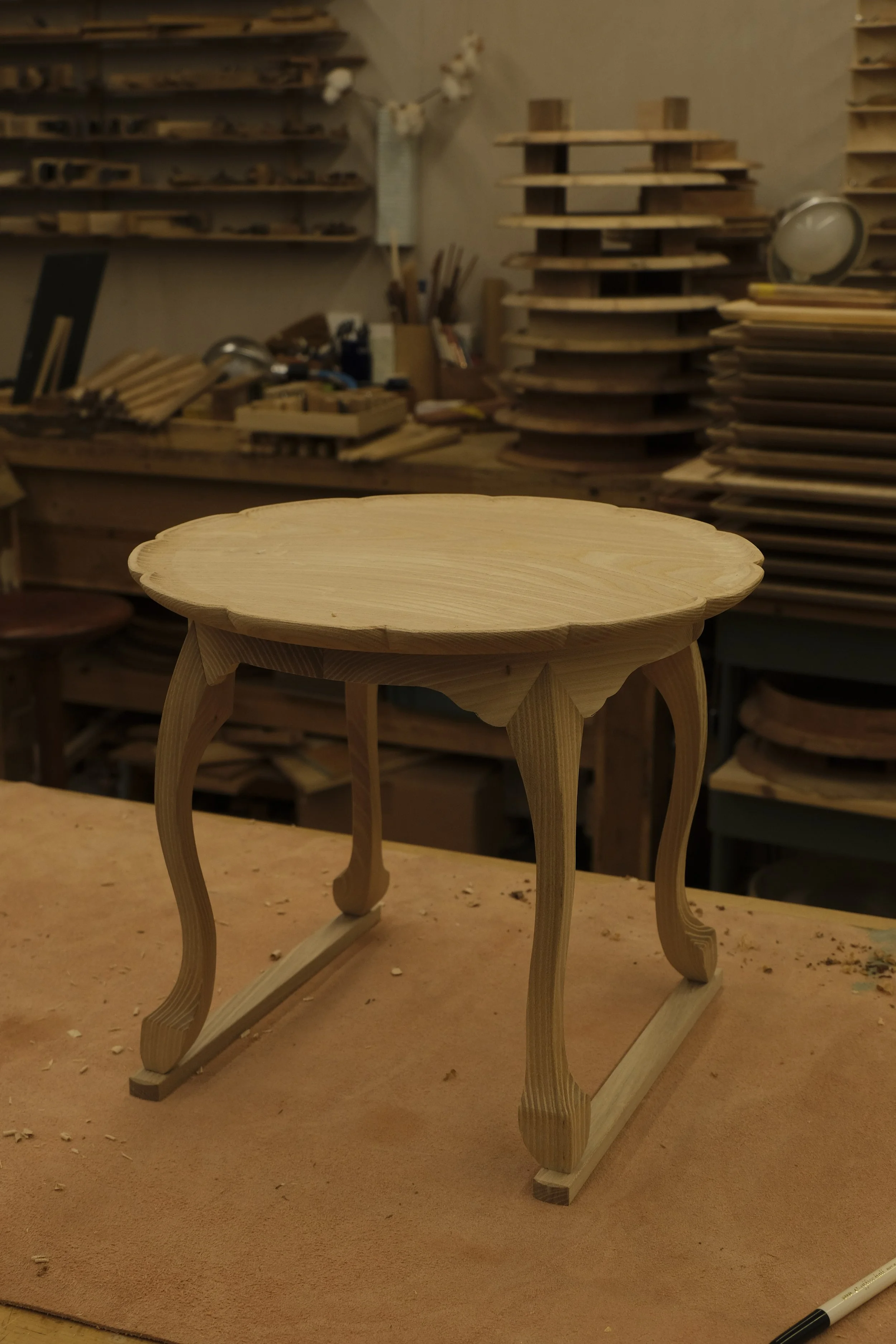 Unfinished wooden side table in a woodworking shop.