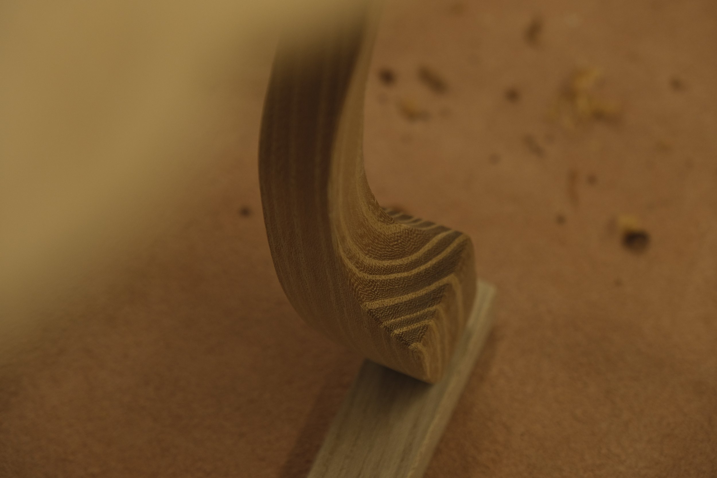 Close-up of a wooden spoon resting on a speckled orange countertop.