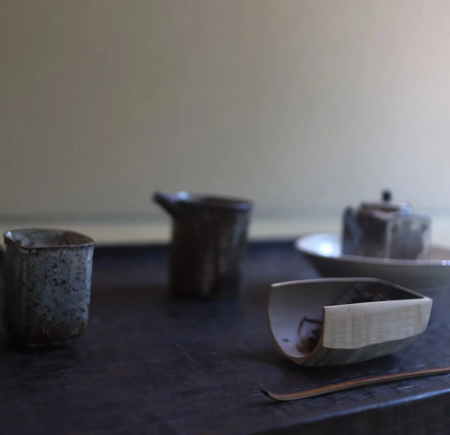 Various ceramic and wooden cups and containers on a dark wooden surface.