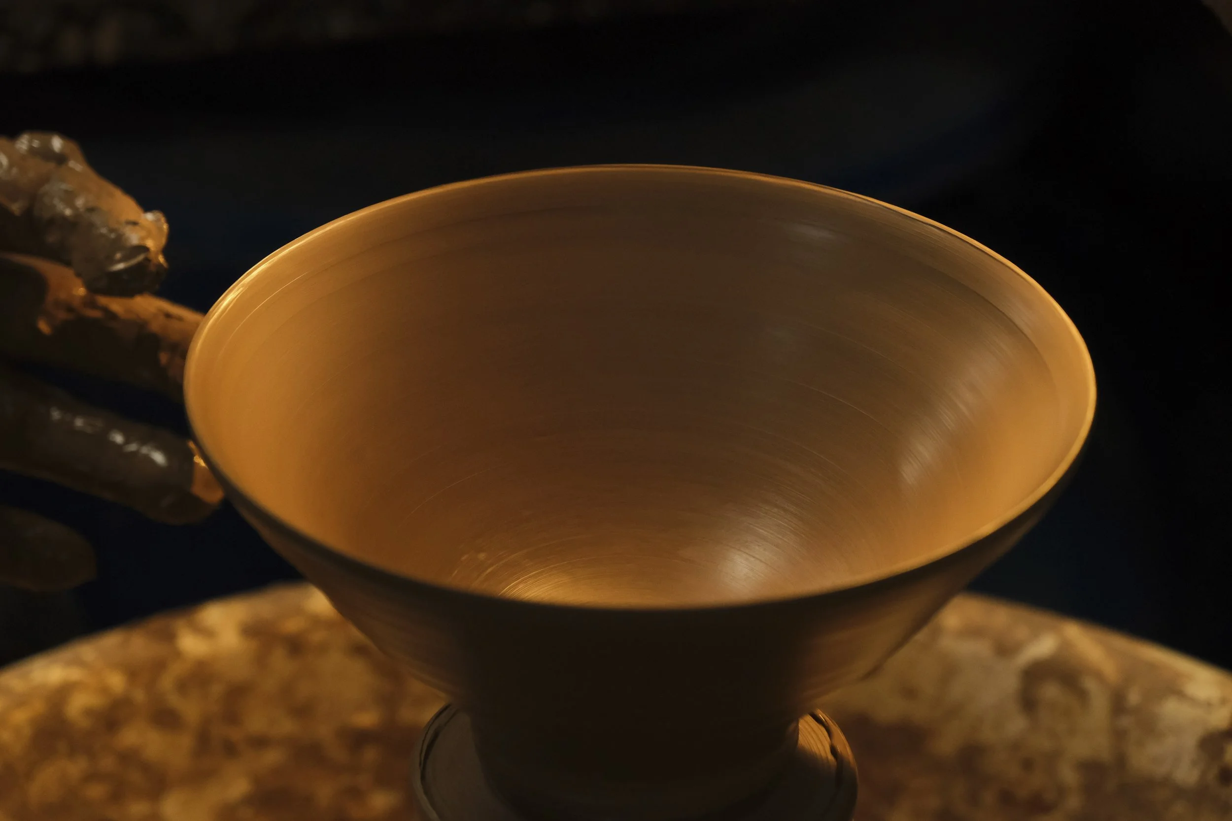 Close-up of a glowing ceramic bowl on a dark background.
