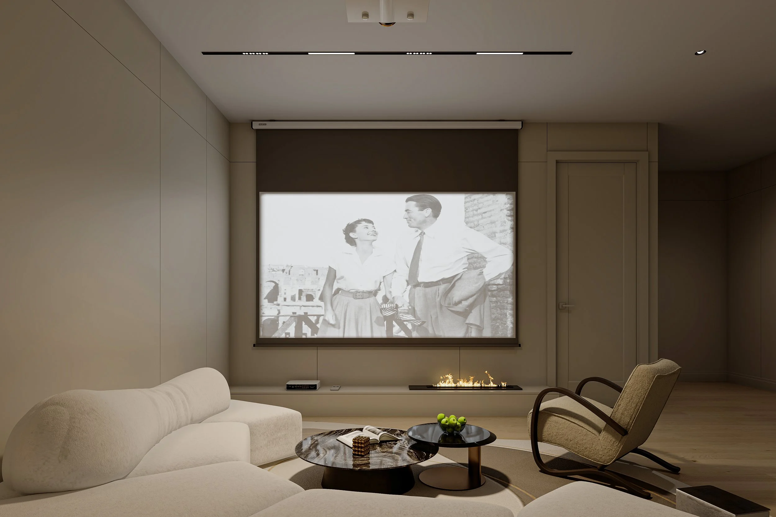 Modern home theater room with a large projector screen displaying a black and white movie scene. The room features a beige sectional sofa, a round coffee table with green apples and books, a rocking chair, and a built-in linear fireplace below the screen.