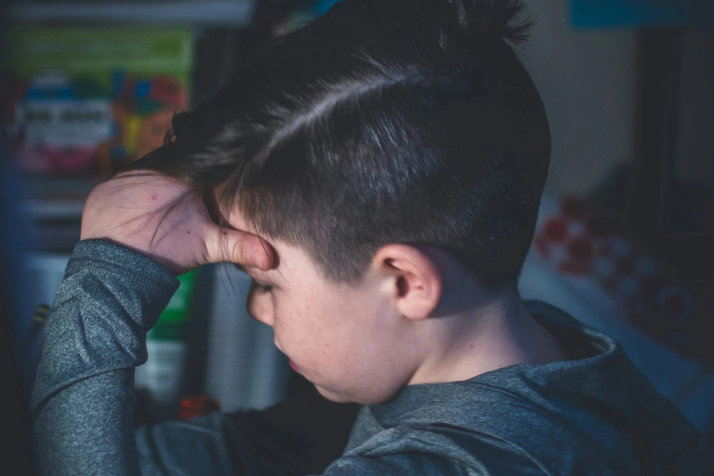 Young boy sitting at desk in classroom holding his head – symbolizing frustration and school mismatch
