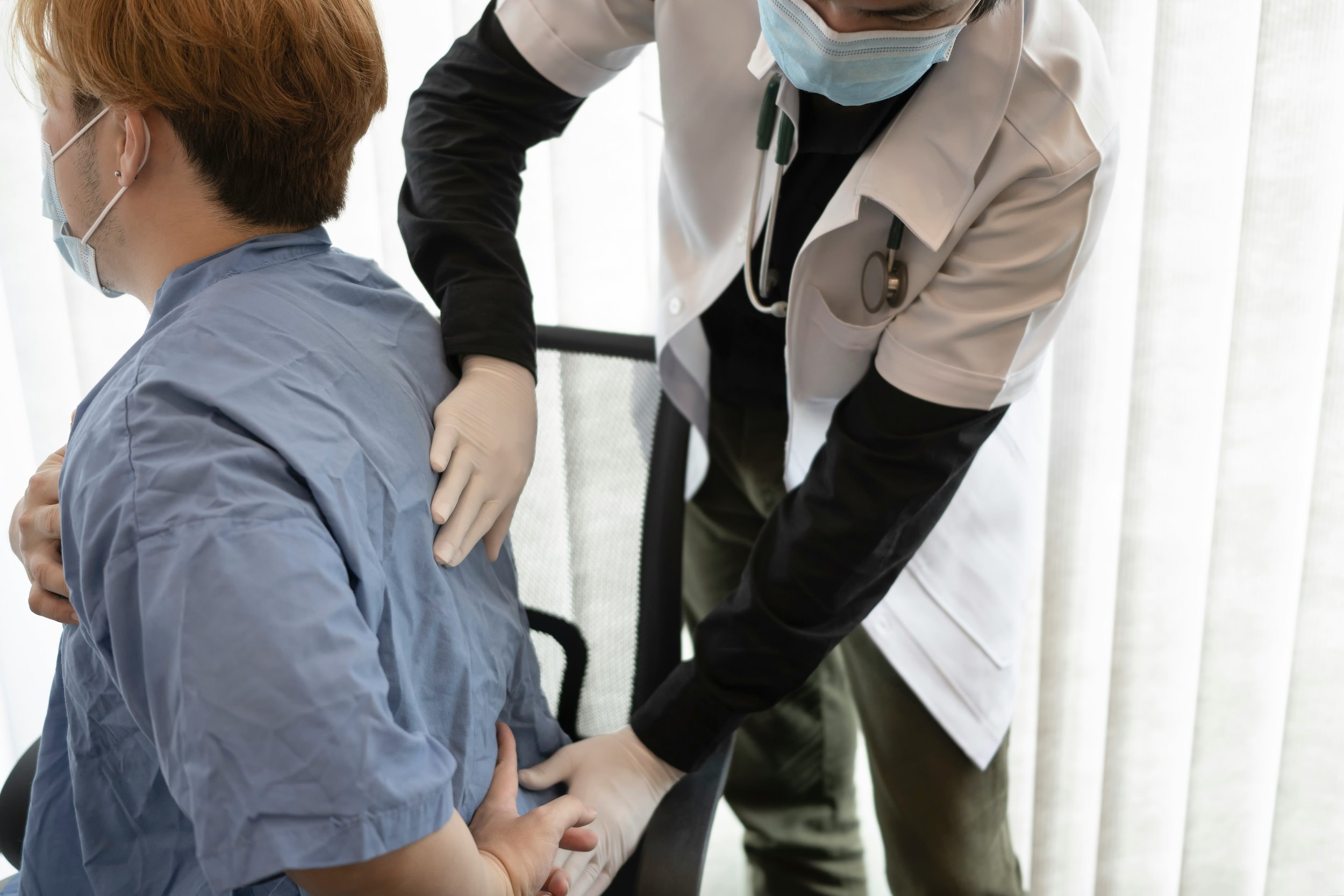 Healthcare professional examining patient's back in clinic