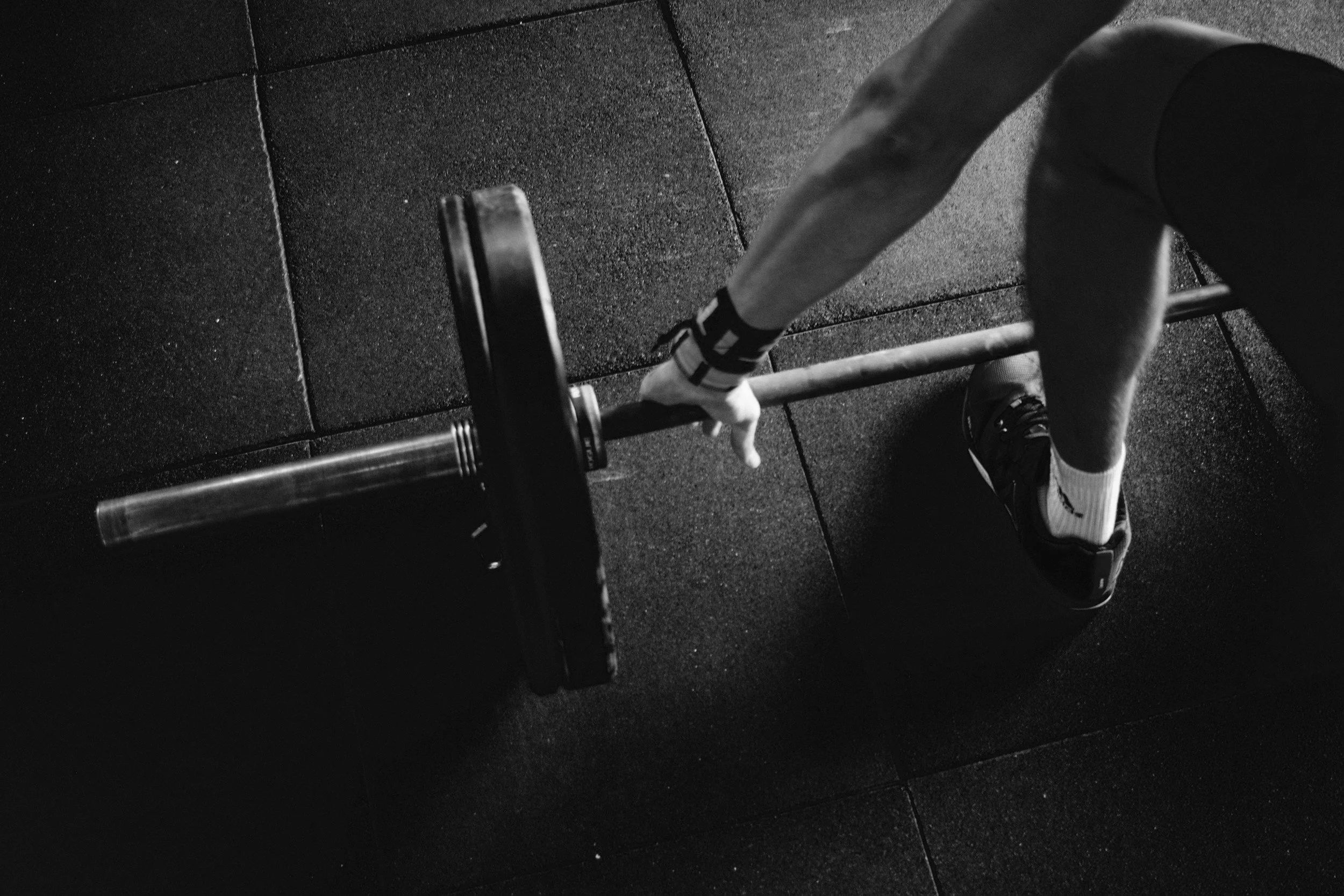 Person lifting a barbell in a gym, black and white photo