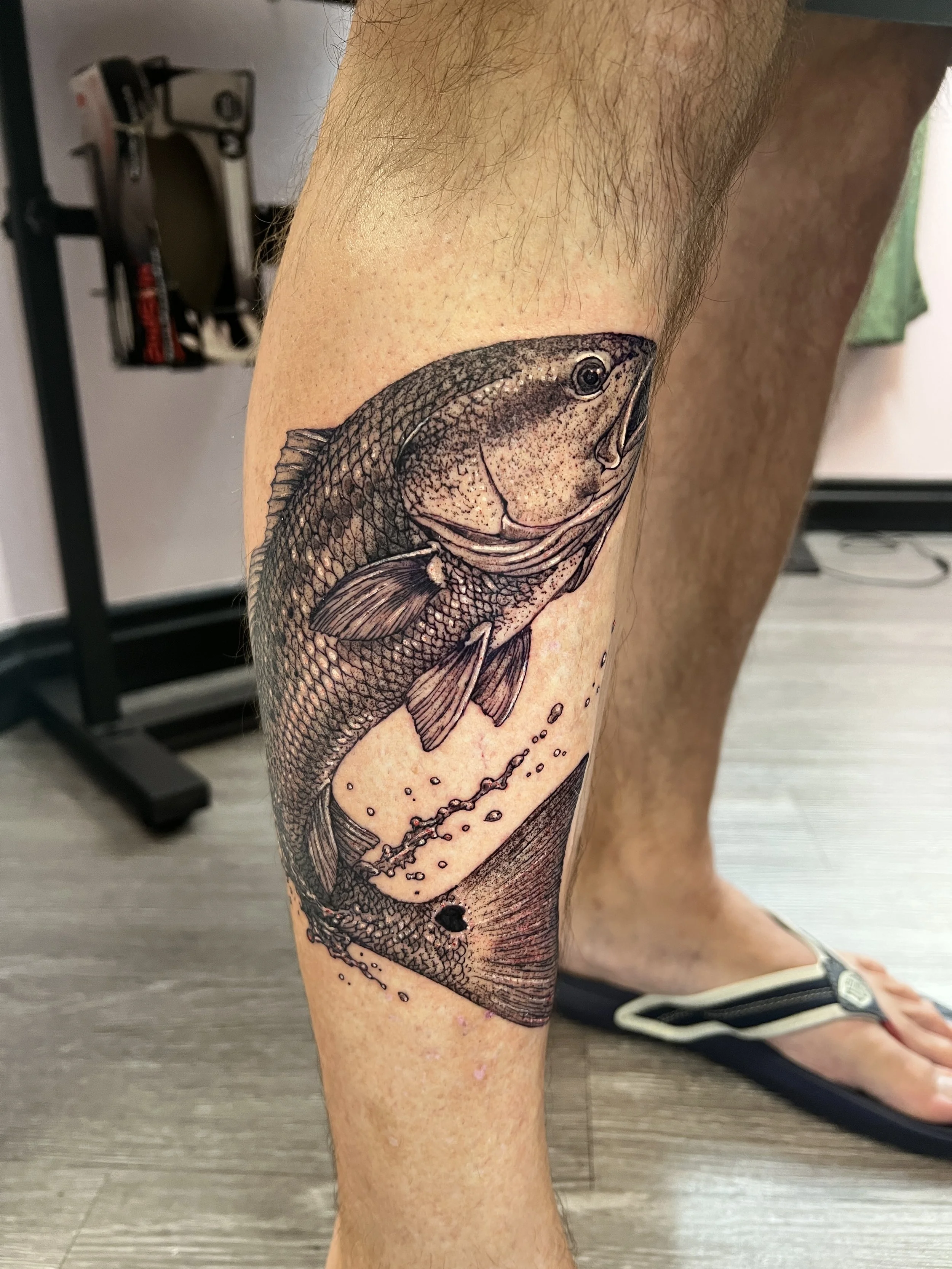 Tattoo of a fish on a person's thigh.