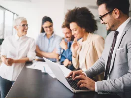 Group of diverse professionals working together around a laptop in a modern office
