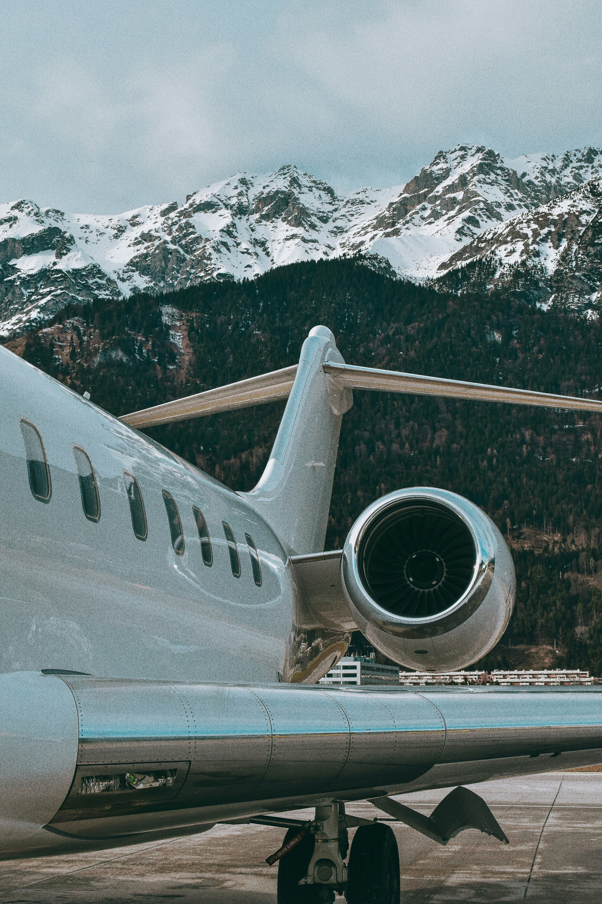 Close-up of a private jet airplane on the tarmac with snow-covered mountains in the background.