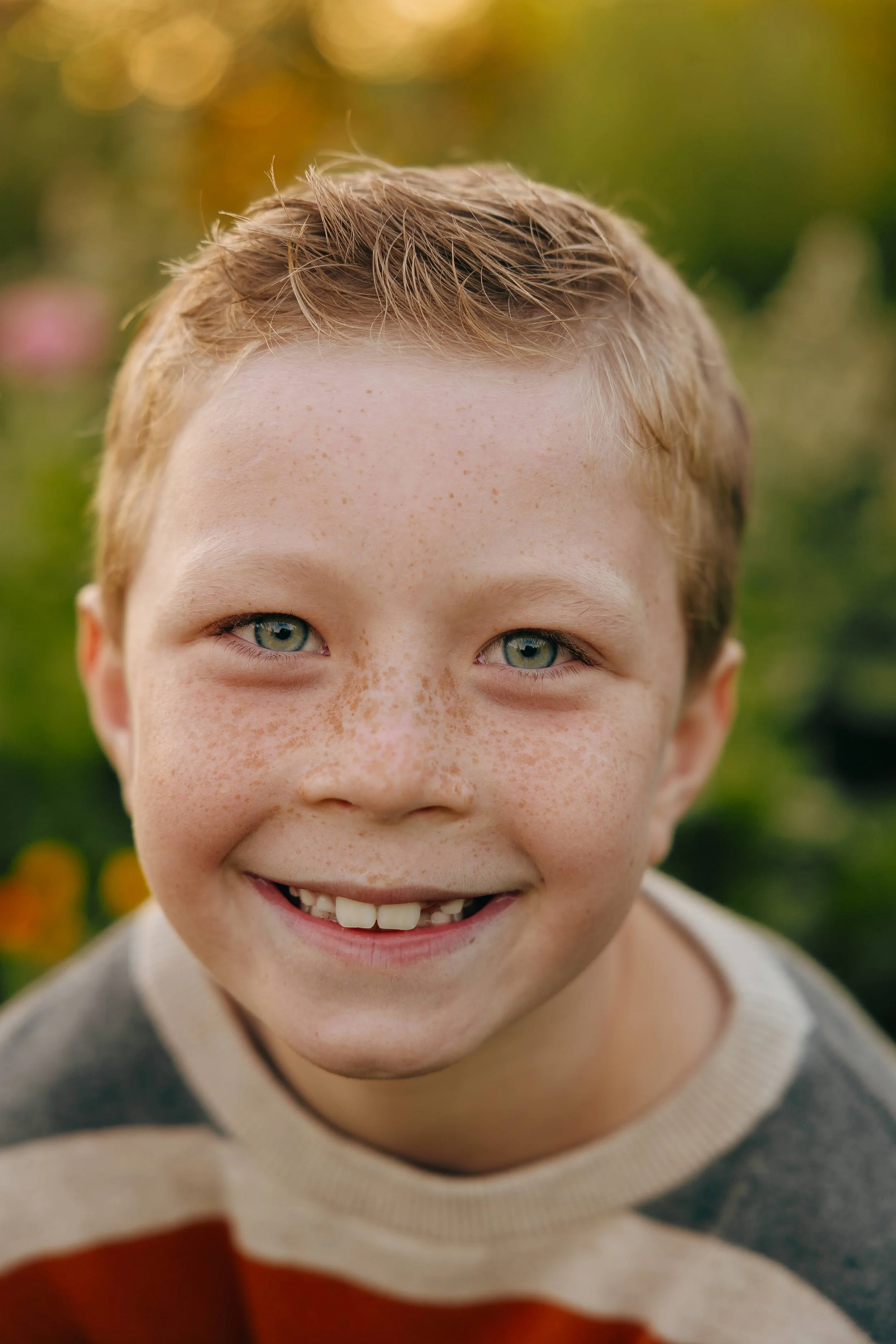 Close-up outdoor portrait of a smiling young boy with freckles taken by a Cary, NC children's photographer