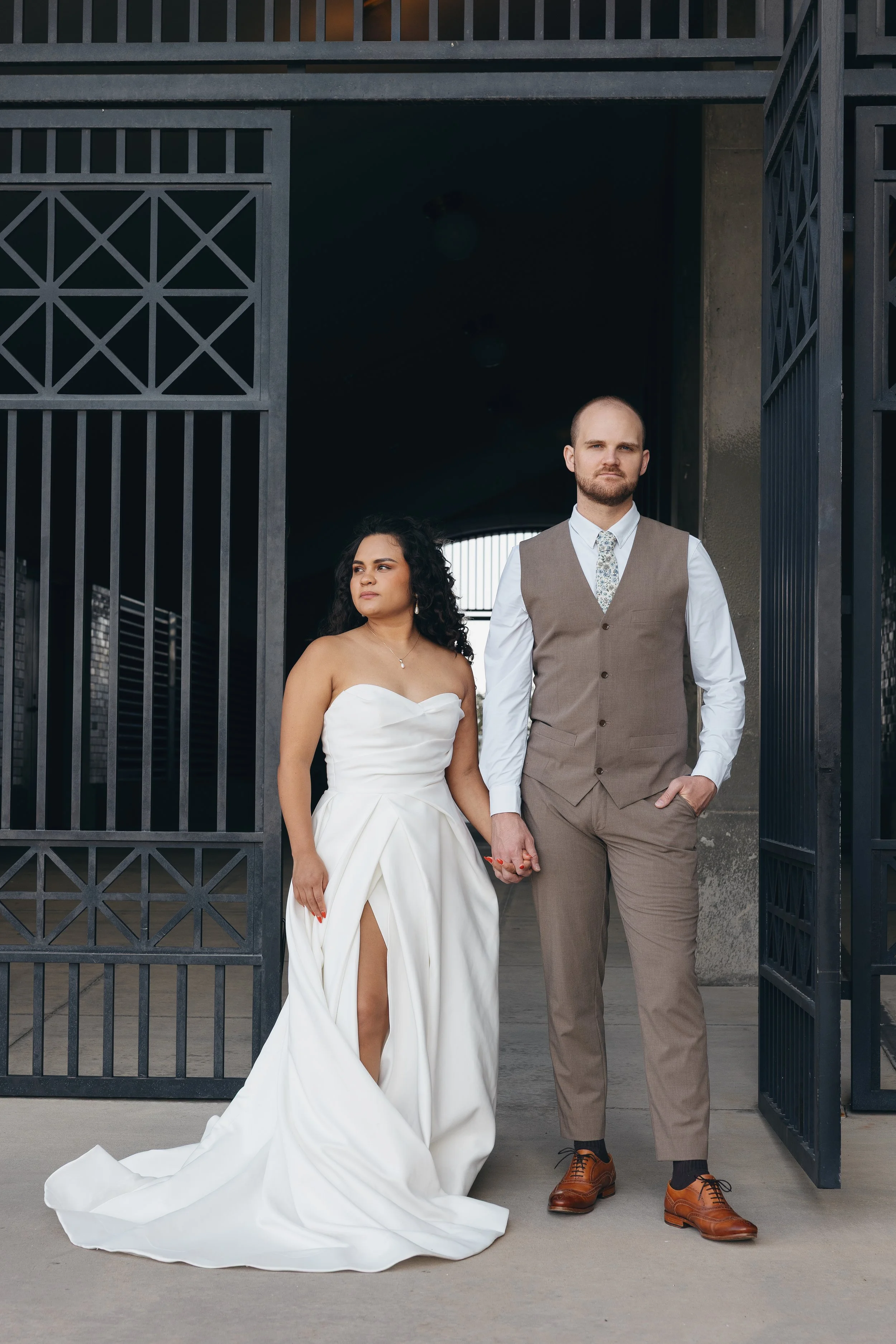 Bride and groom holding hands at an industrial-style venue entrance during a wedding portrait in Chapel Hill, NC
