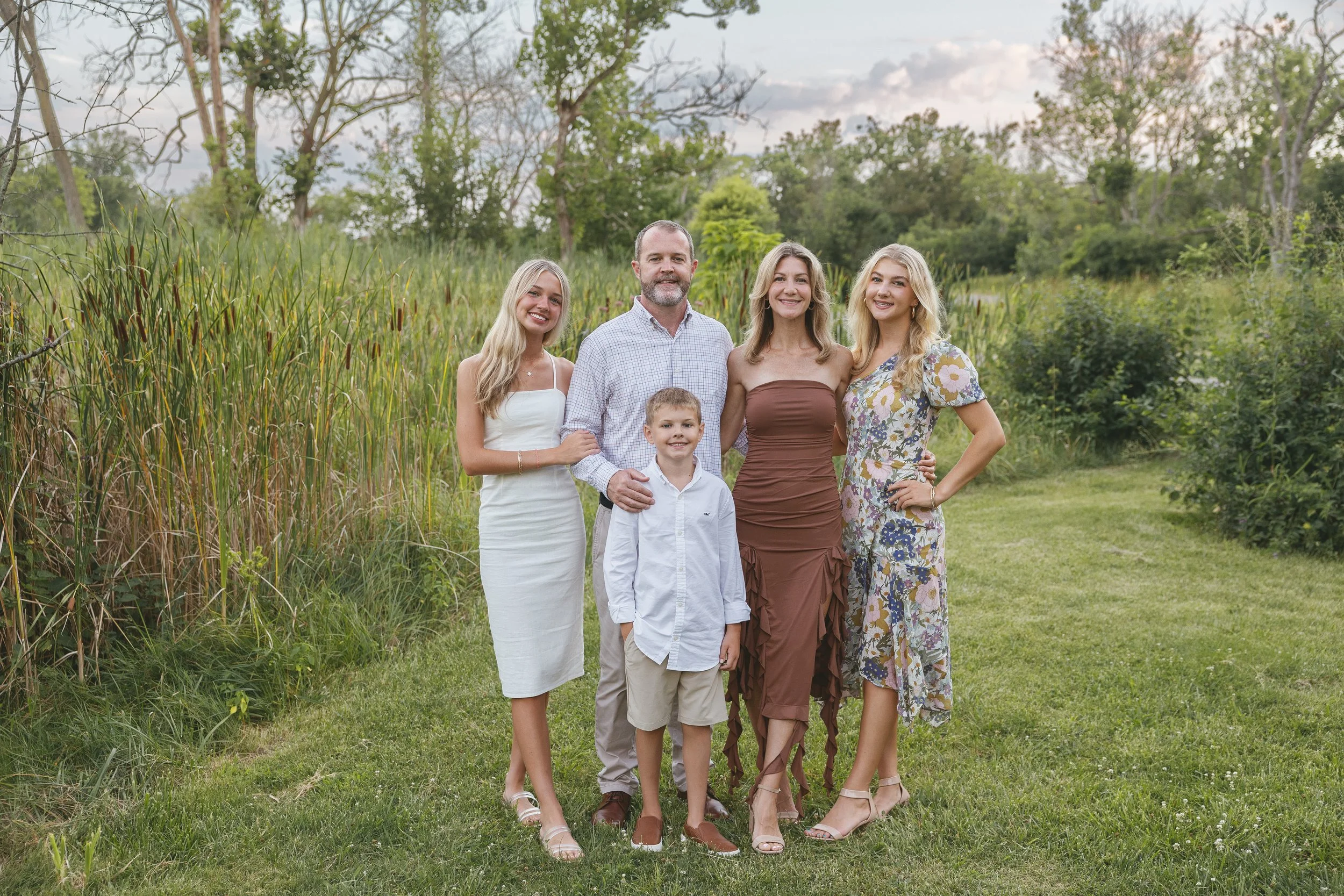 Family of five smiling together outdoors during a family portrait session near Apex, NC