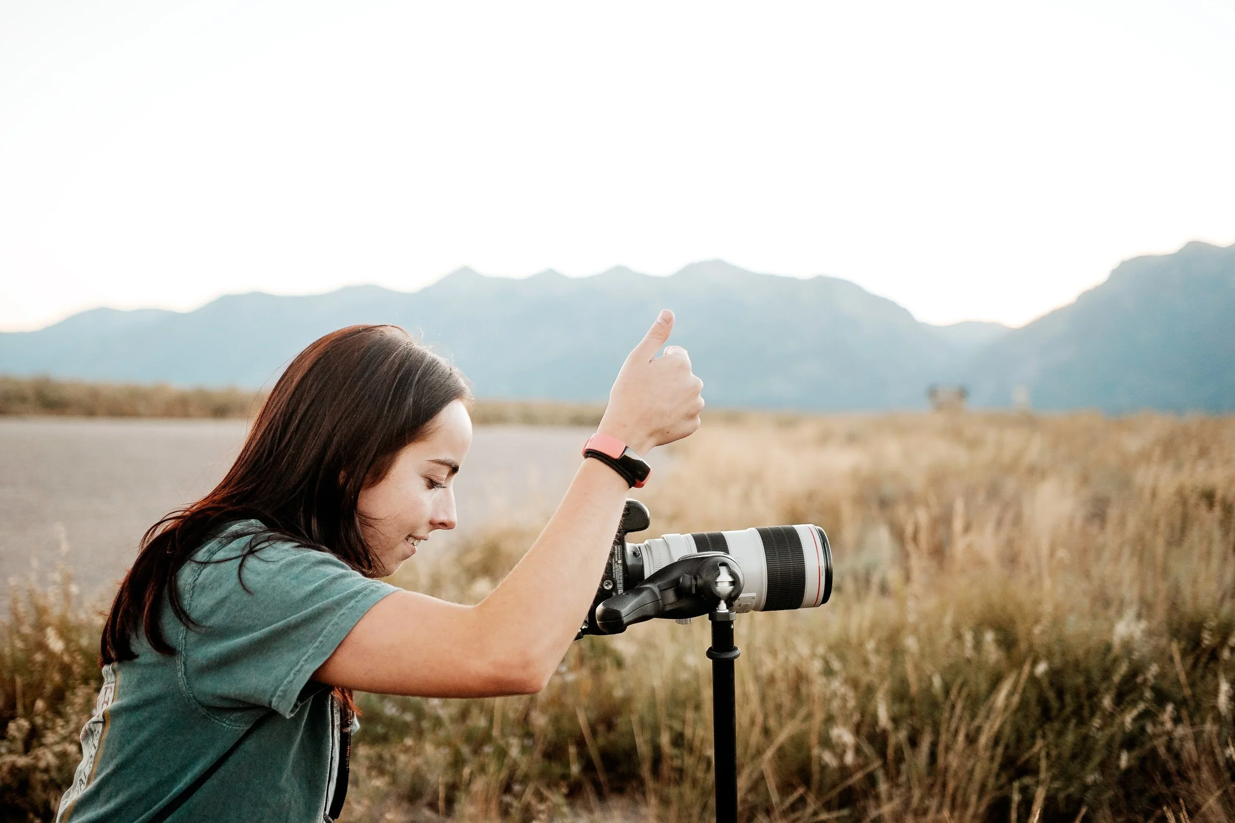 Open notebook with lined pages, white tulips, a lit white candle in a glass holder, and a white surface background.