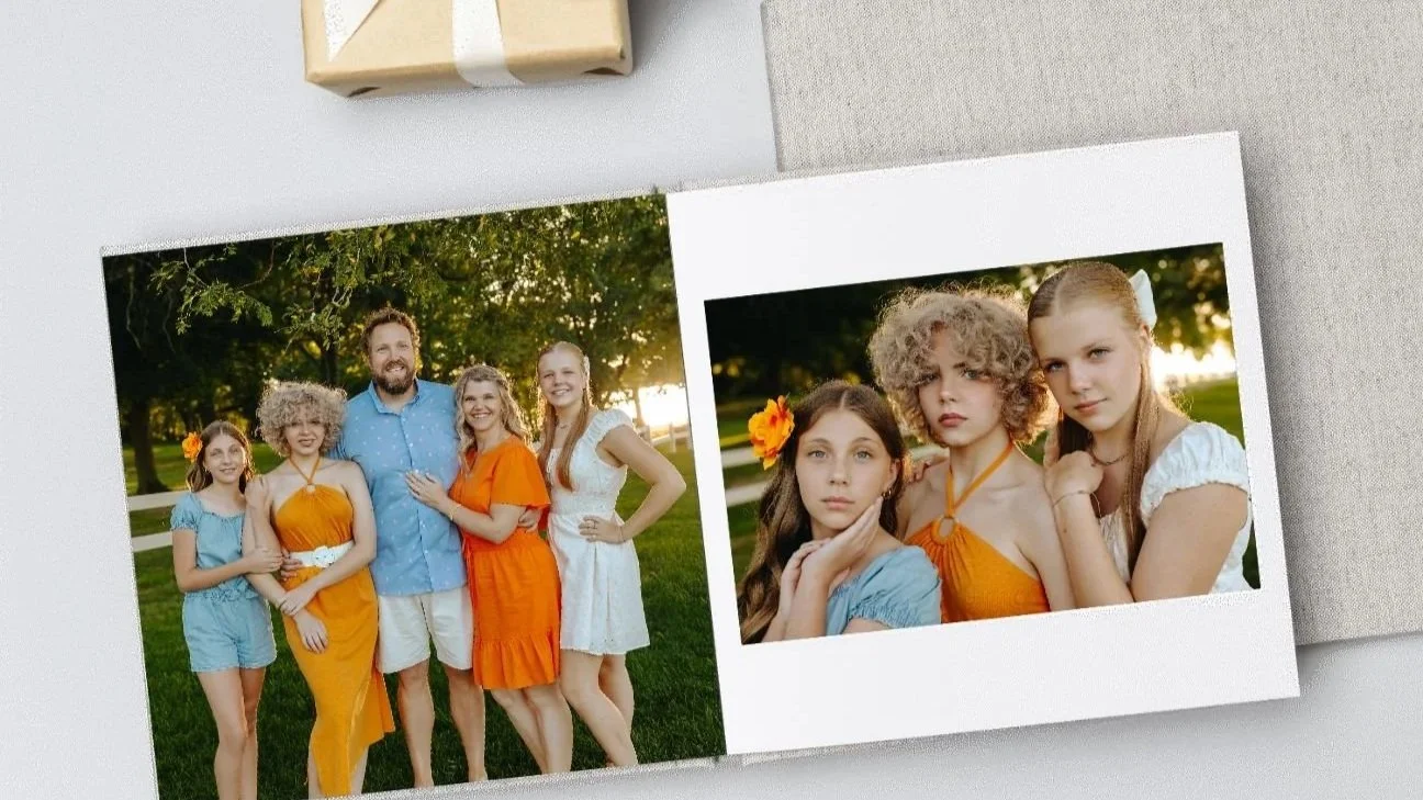 Photograph of a family of five with three young girls and two adults in a park during sunset, with the girls dressed in blue and orange, and one girl wearing a flower in her hair. The photo is printed in a book or album, with a small package visible at the top.
