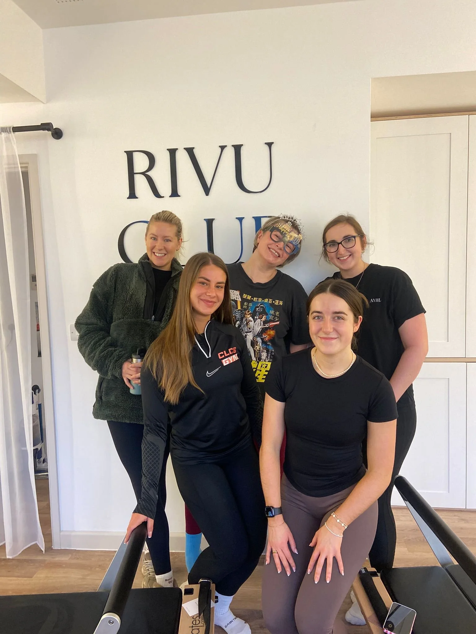 Rivu Club Member Milestones - Group of five women standing together indoors, smiling, in front of a wall with the letters RIVU and CUI.