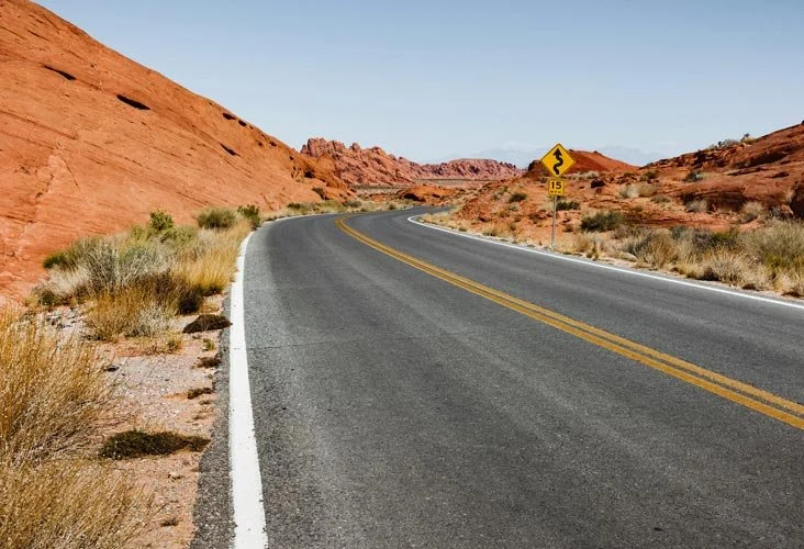 A paved road between desert landscape.