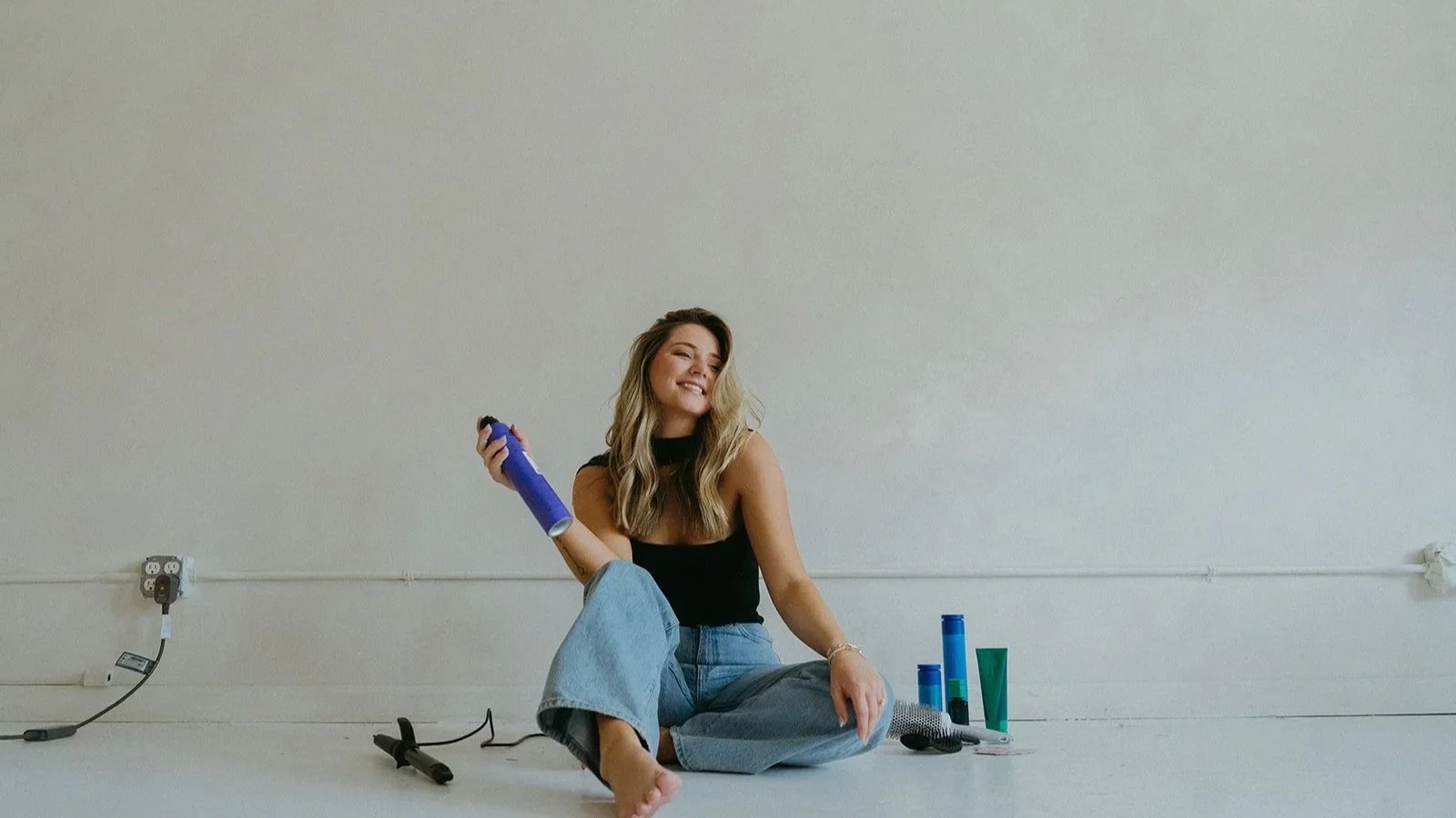 Chloe Webster, blending and grey-blending specialist, showcasing professional haircare products at Salon Janae.