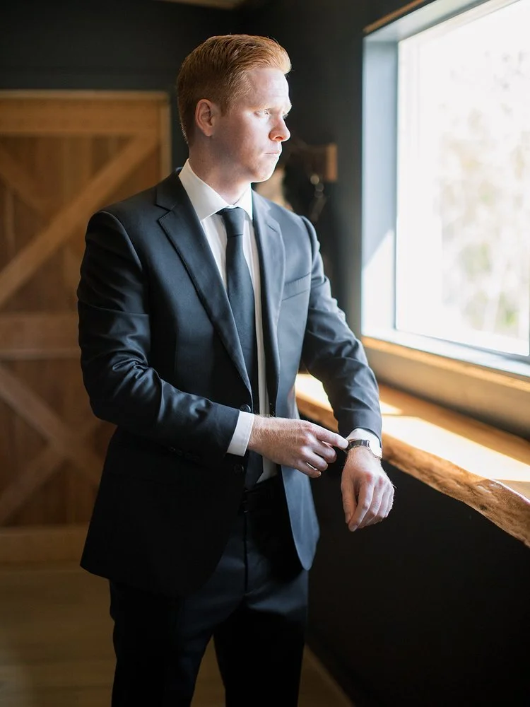 Groom getting ready in barn in black suit