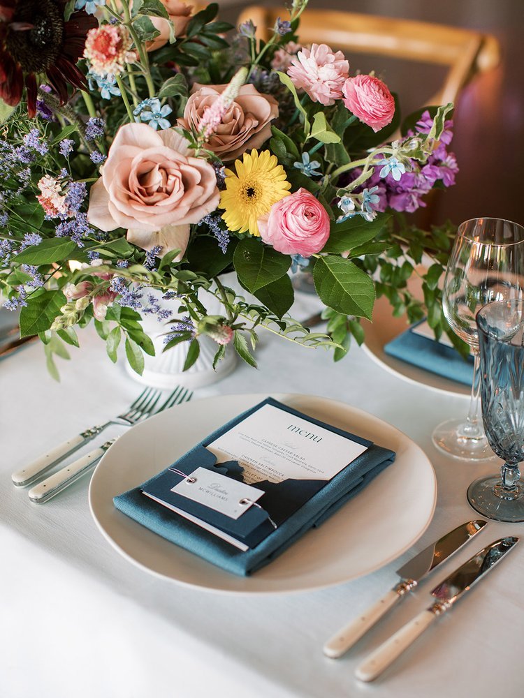 White and blue wedding Place setting and colorful pink yellow purple and blue wildflower style wedding flowers | Shannon rose events