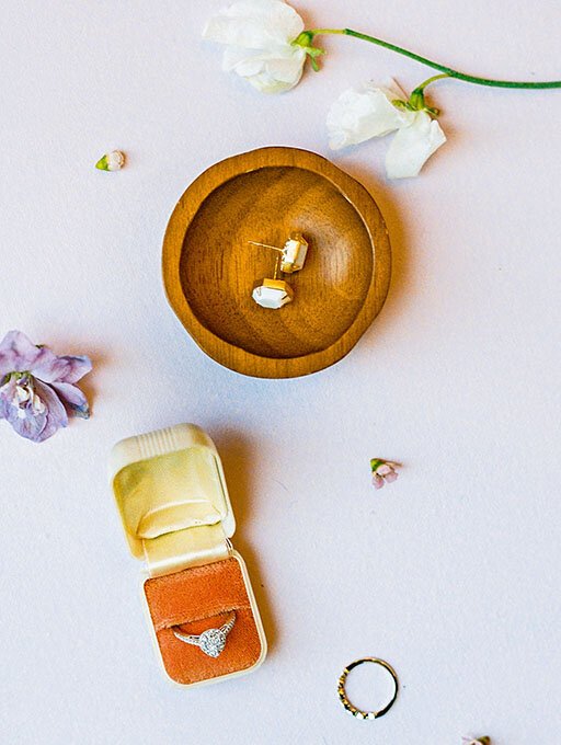 Earrings in wood dish with a wedding ring in a orange vintage ring box