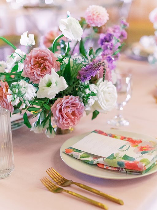 Feminine place setting with a floral napkin and purple flower arrangement