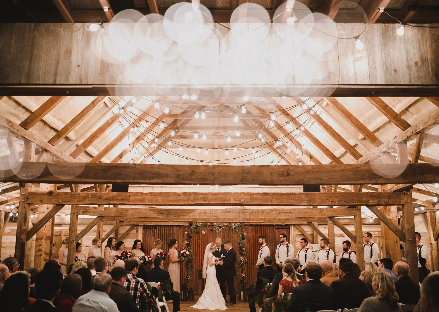 Hollow Hill Farm Event Center Wedding ceremony in wooden barn with cafe lights