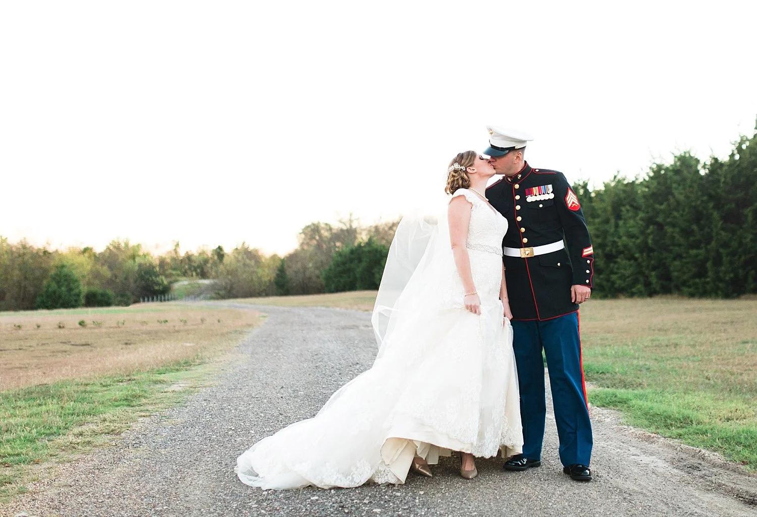Castle at Rockwall wedding bride and marine groom kissing on gravel road