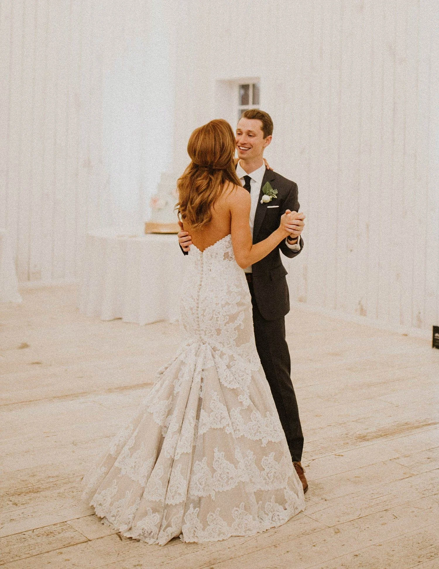 Bride wearing nude and lace dress while dancing with groom