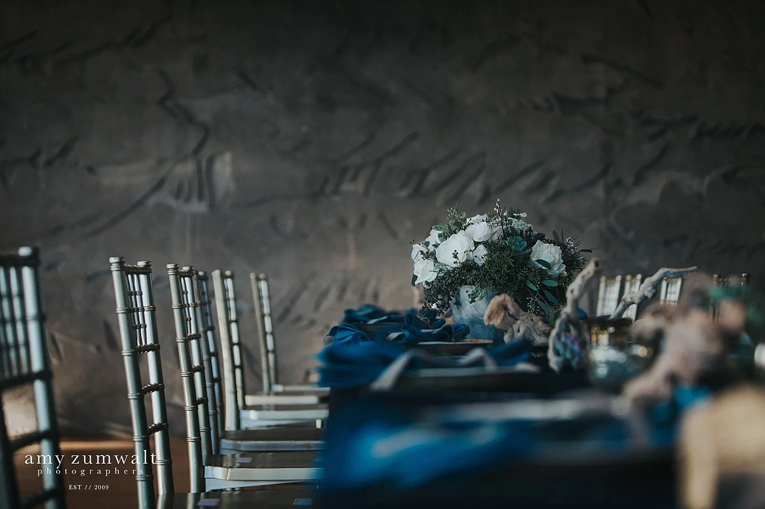 Fall greenery arrangement on navy linens and chivari chairs